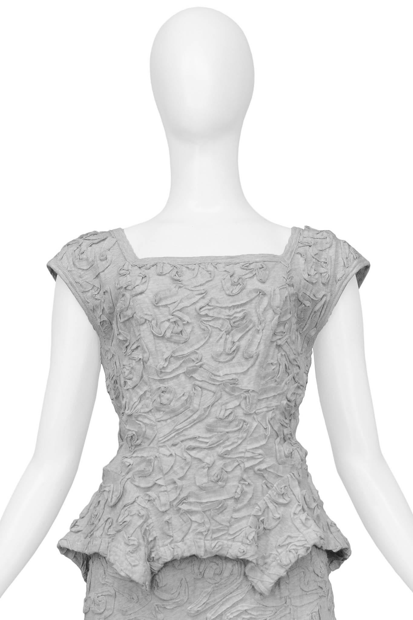 Resurrection Vintage is excited to offer a vintage Comme des Garcons grey top and skirt ensemble with ribbon detailing. The ensemble features a cap-sleeve design and square neckline top, embossed ribbon detailing throughout, and fitted knee-length
