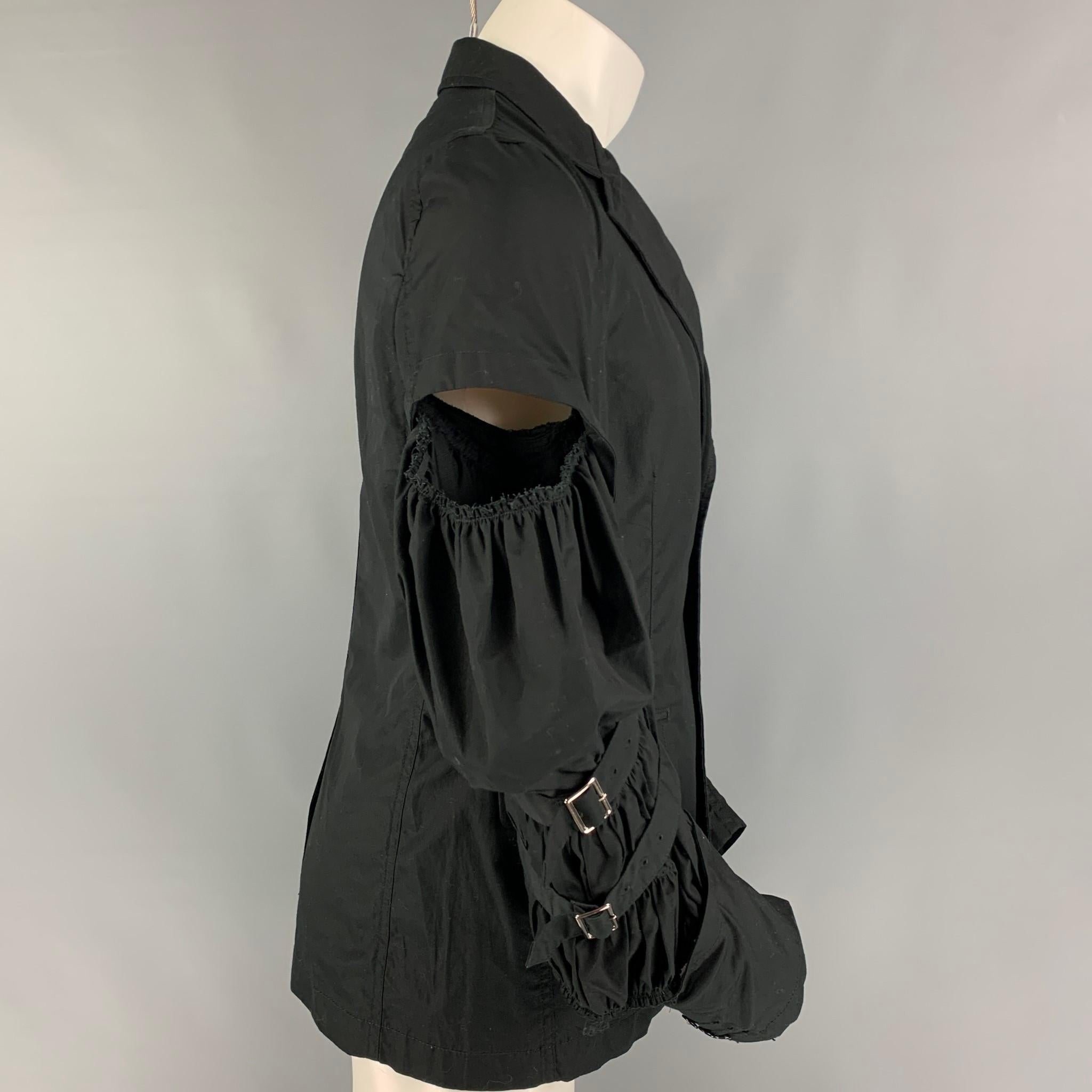 COMME des GARCONS HOMME PLUS jacket comes in a black cotton featuring a notch lapel, flap pockets, single back vent, cut out design, pleated details, buckle straps, and a double button closure. Made in Japan. 

Very Good Pre-Owned Condition.
Marked: