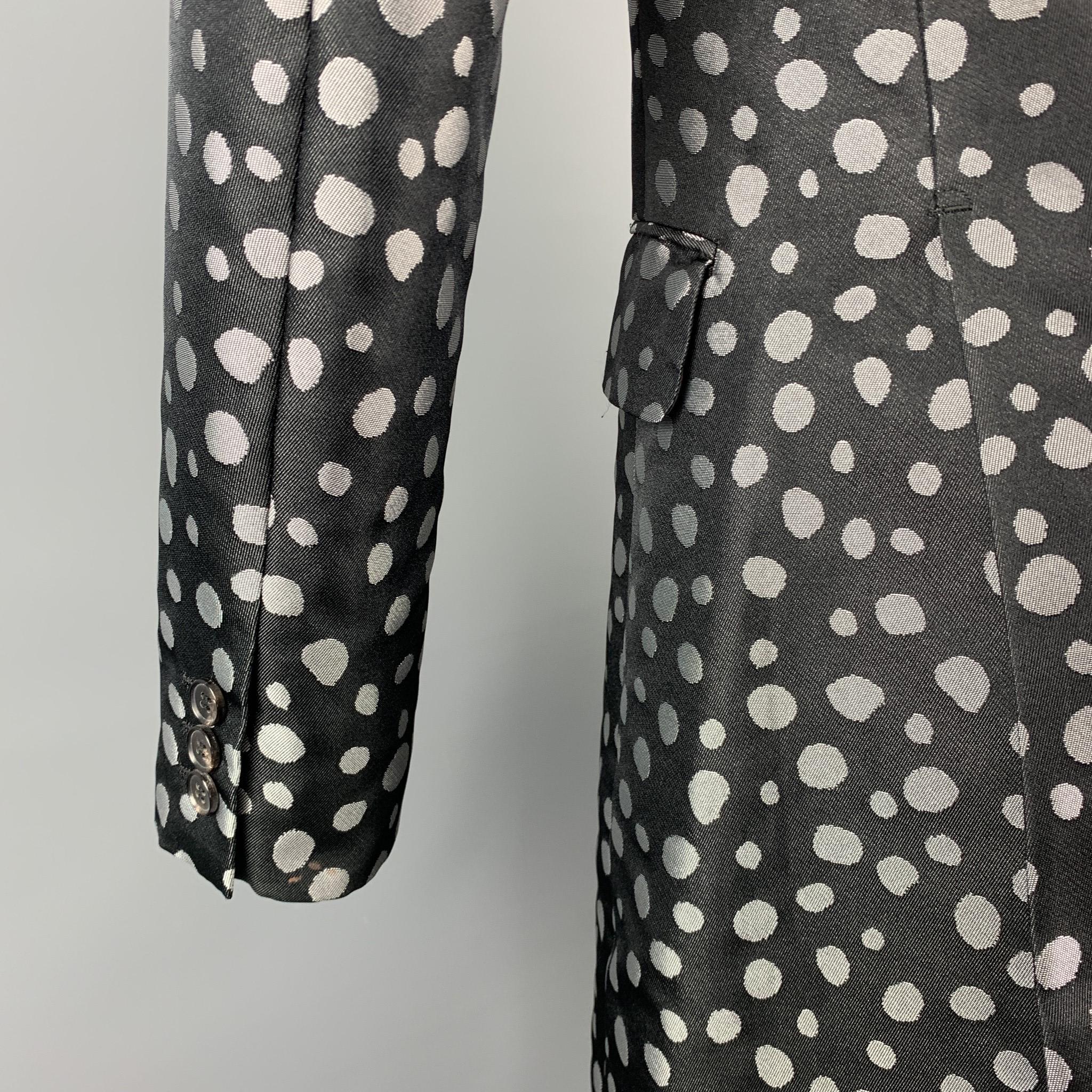 COMME des GARCONS HOMME PLUS coat comes in a black & silver dot print polyester with a half black liner featuring a notch lapel, flap pockets, double back vent, and a three button closure. Made in Japan.

Excellent Pre-Owned Condition.
Marked: JP S