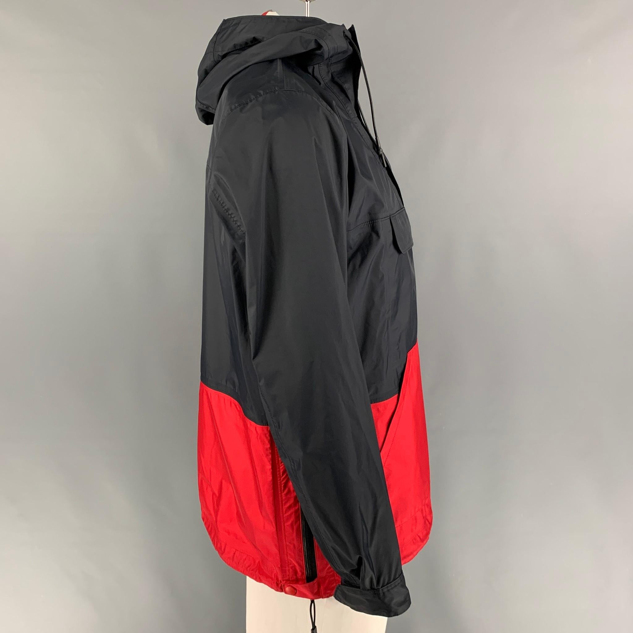 COMME des GARCONS HOMME jacket comes in a navy & red color block nylon featuring a windbreaker style, hooded, front pockets, drawstring, and a half zip up closure. Made in Japan. 

Very Good Pre-Owned Condition.
Marked: L

Measurements:

Shoulder: