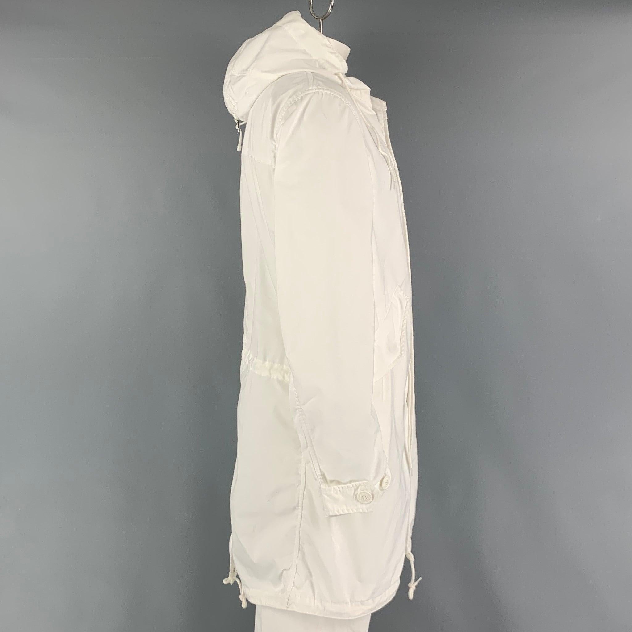 COMME des GARCONS HOMME AD2018 long coat comes in a white polyester material featuring a parka hooded style, large flap pockets, oversized fit, drawstring details, and a hidden zip & snap button closure. Made in Japan.Very Good Pre-Owned