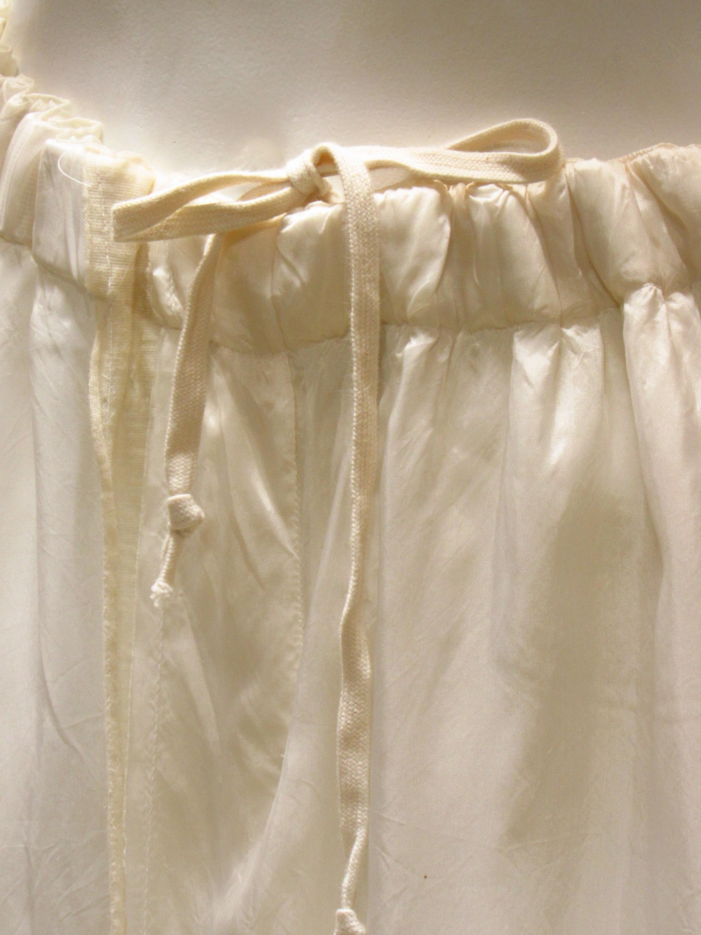 Delicate double-layered cream-colored rayon skirt is vintage Comme des Garçons, featuring a contrasting fabric front seam and the comfort of an elasticized waistband with an inner drawstring for personalized fit. There are two side-seam pockets and
