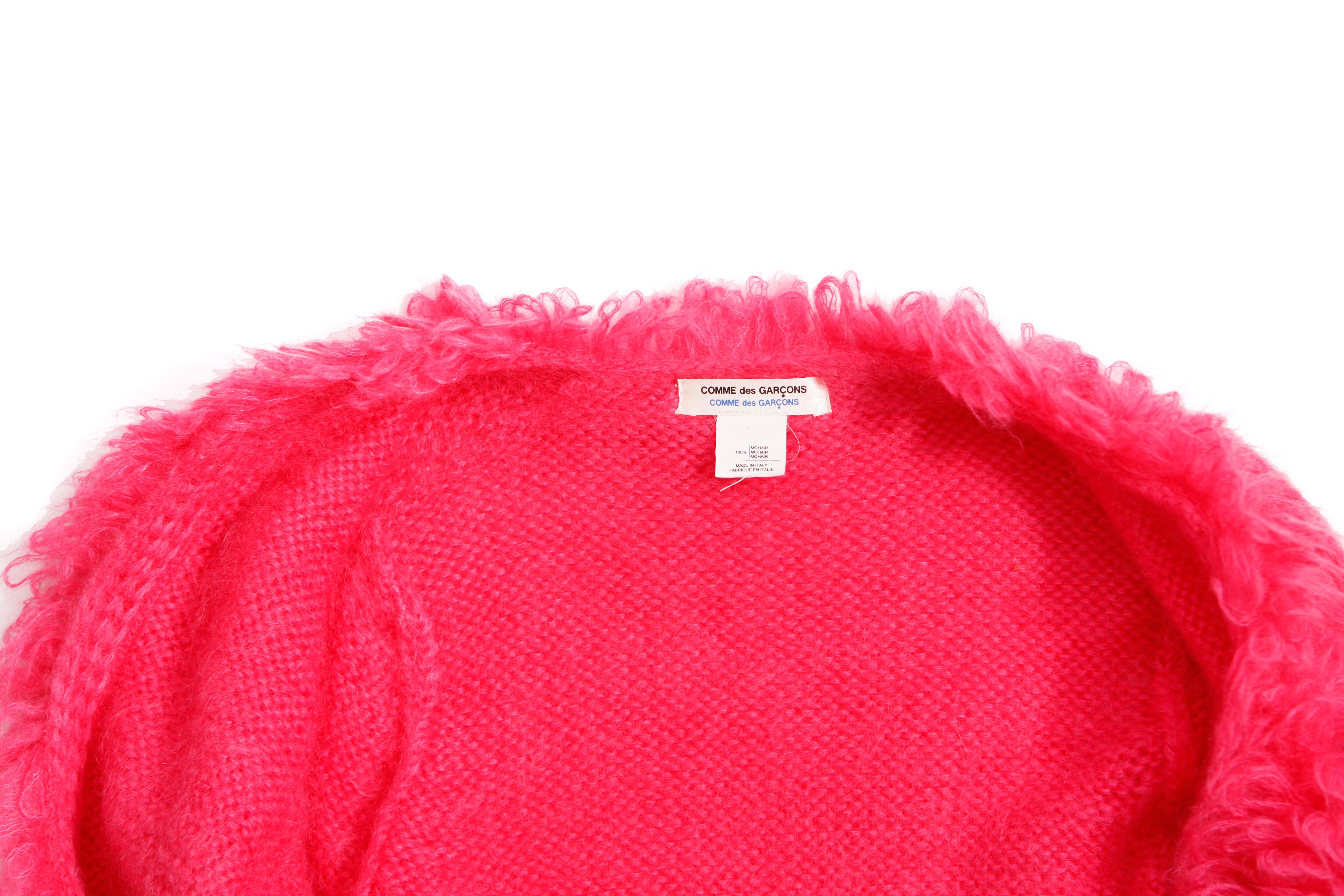 Comme des garçons, Mohairweste mit Sicherheitsnadel in fluoreszierendem Rosa in Größe S. Dieses Produkt ist neu/ungetragen.

- • ZUSTAND: neu

- • GRÖSSE: S

- • MASSNAHMEN: Länge 64 cm, Brustumfang 46 cm, Schulterlänge 37 cm (von Schulter zu