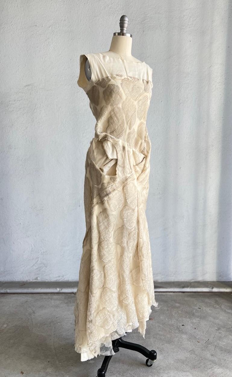 Resurrection Vintage è lieta di offrire un abito vintage Comme des Garçons in organza e mussola di colore bianco sporco, caratterizzato da un top in organza vintage con un disegno floreale in lame dorate, una sottoveste in mussola e una gonna a