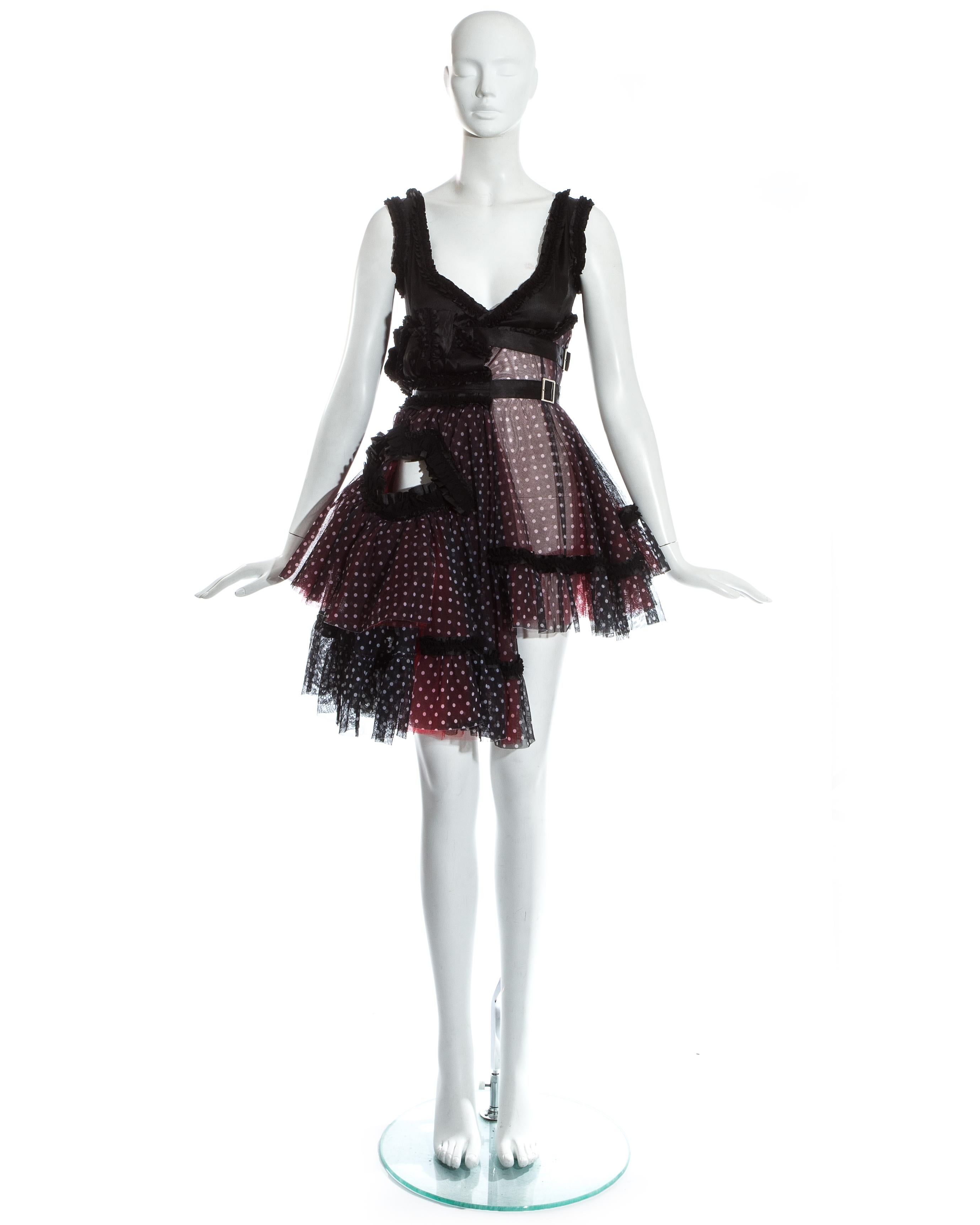 Comme des Garcons; black polka dot tulle and satin mini dress. Two signature lip shaped cut outs at the front and back, ruffled trimmings throughout, voluminous skirt with layers of red and black tulle and two waist belts with silver buckle