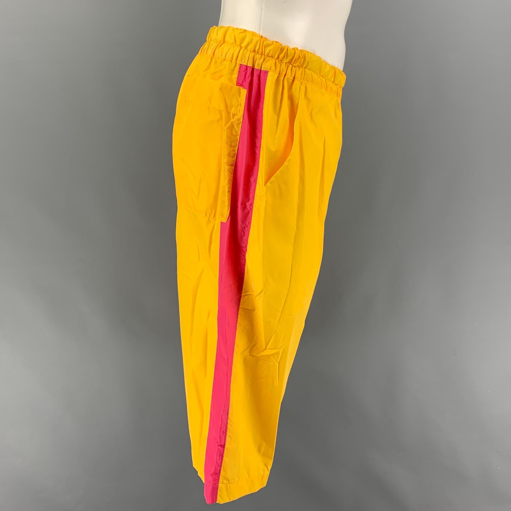 COMME des GARCONS SHIRT shorts comes in a yellow polyamide with a nylon net lining featuring a pink stripe, back pockets, elastic waist, drawstring, and a zip fly closure. Made in Japan. 

New With Tags. 
Marked: S

Measurements:

Waist: 32