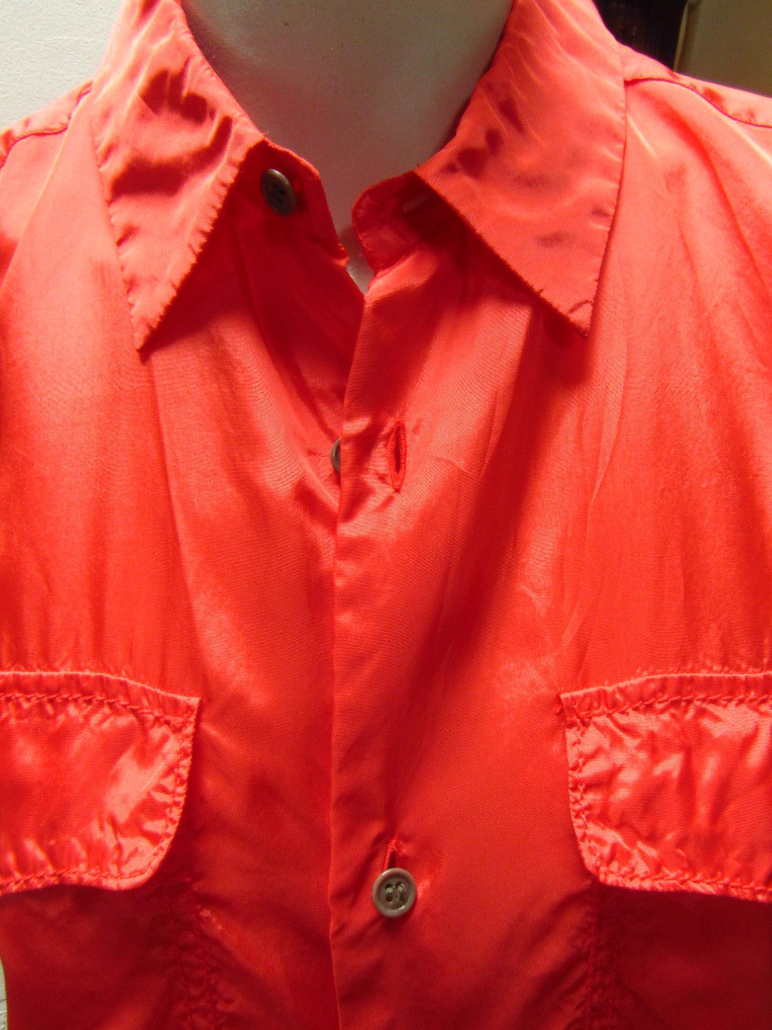This summery Comme des Garçons top is made of a lightweight rayon. The vibrant coral lends a colorful twist  to this classic style, complete with two breast pockets and short sleeves. 