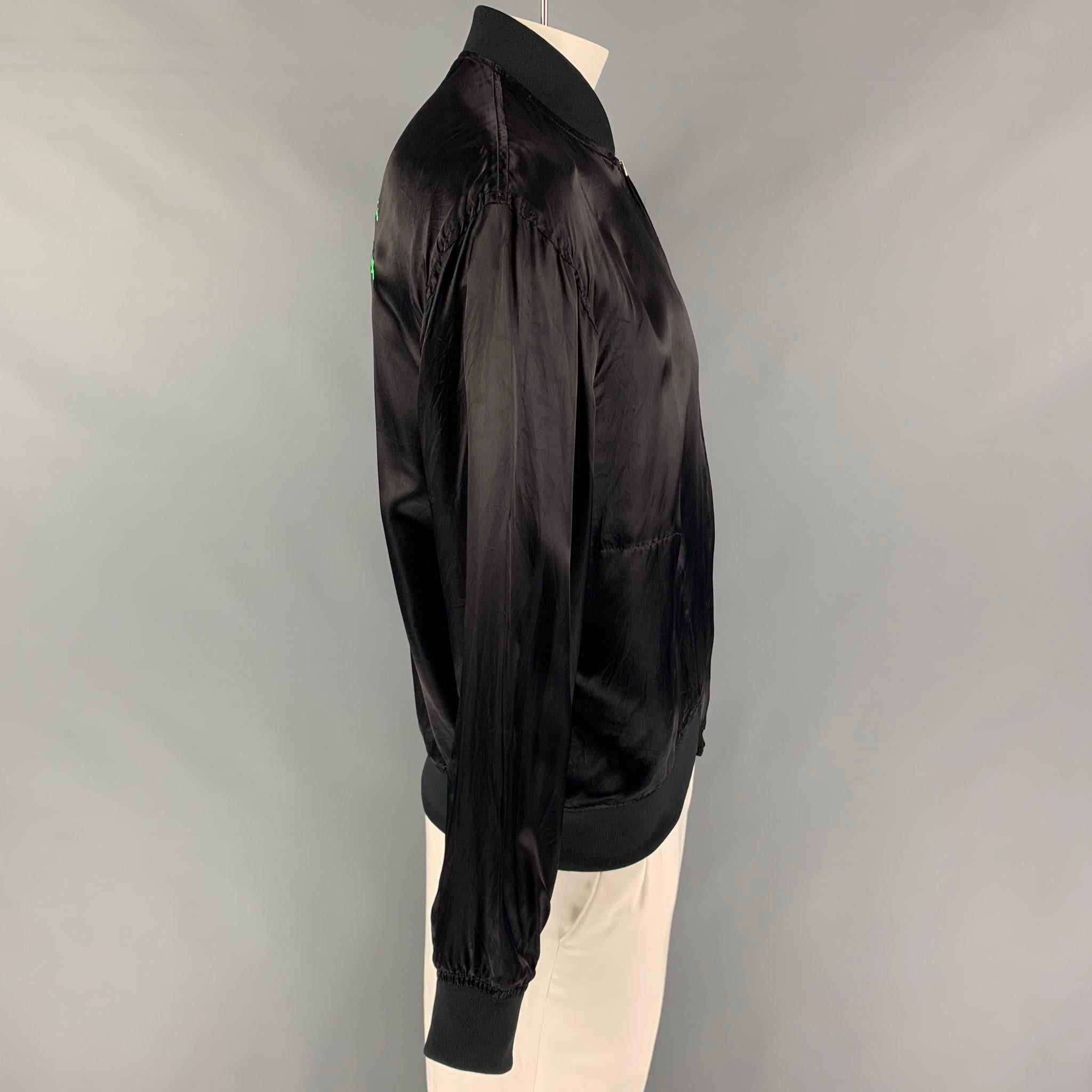 COMME des GARCONS jacket comes in a black cupro with a back green logo design featuring a bomber style, ribbed hem, slit pockets, and a full zip up closure. Made in Japan. 

Excellent Pre-Owned Condition.
Marked: XL /