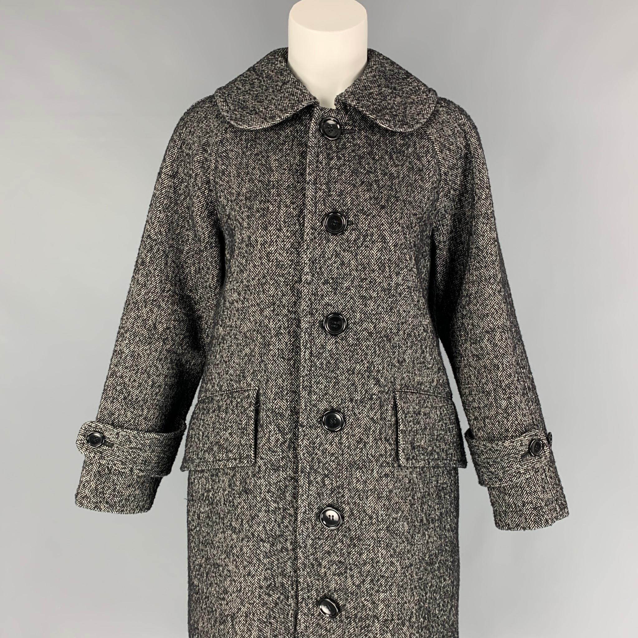 COMME des GARCONS TRICOT coat comes in a black & white herringbone wool blend with a full liner featuring a large collar, back strap, flap pockets, and a buttoned closure. Made in Japan. 

Excellent Pre-Owned Condition.
Marked: M /