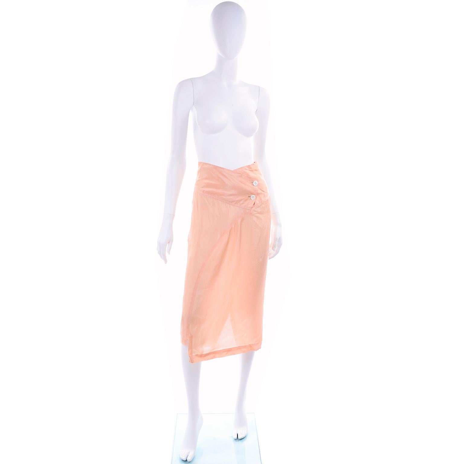 This is a great vintage 1990's Comme Des Garçons peach rayon skirt. The skirt has a double button closure ib the wide waistband. We love the way the waist dips to a slight V. There is a back slit and asymmetrical hemline. This is such an easy to
