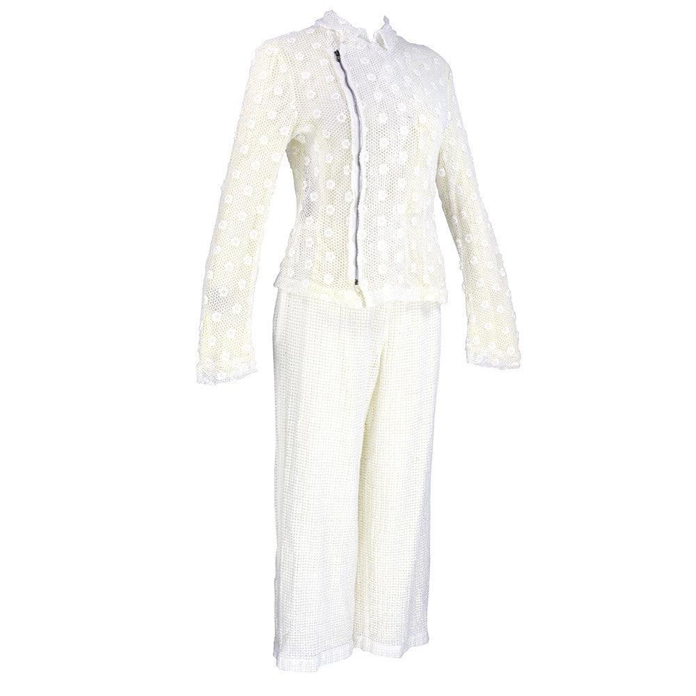 Desde 2004. Conjunto de dos piezas en ojal blanco de mezcla de poliéster y algodón. Chaqueta con cremallera delantera asimétrica - medio forrada. Los pantalones son de cintura elástica, totalmente forrados y recortados. Excelente estado.  Nunca