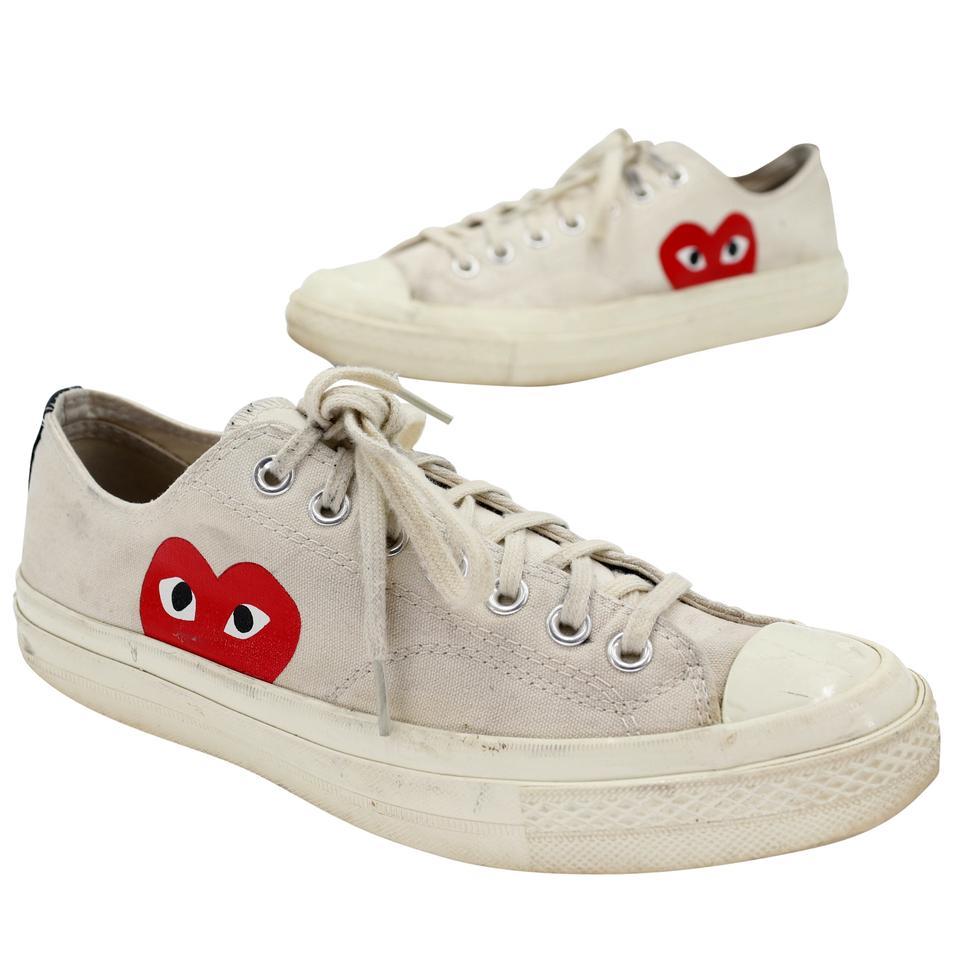 Converse Edition Chuck Taylor All-Star '70 Sneakers. Part of the Comme des Garcons Play x Converse collaboration these Low-top canvas sneakers in beige feature a round rubber cap toe in off-white. Logo graphic printed in red at outer side. Eyelet