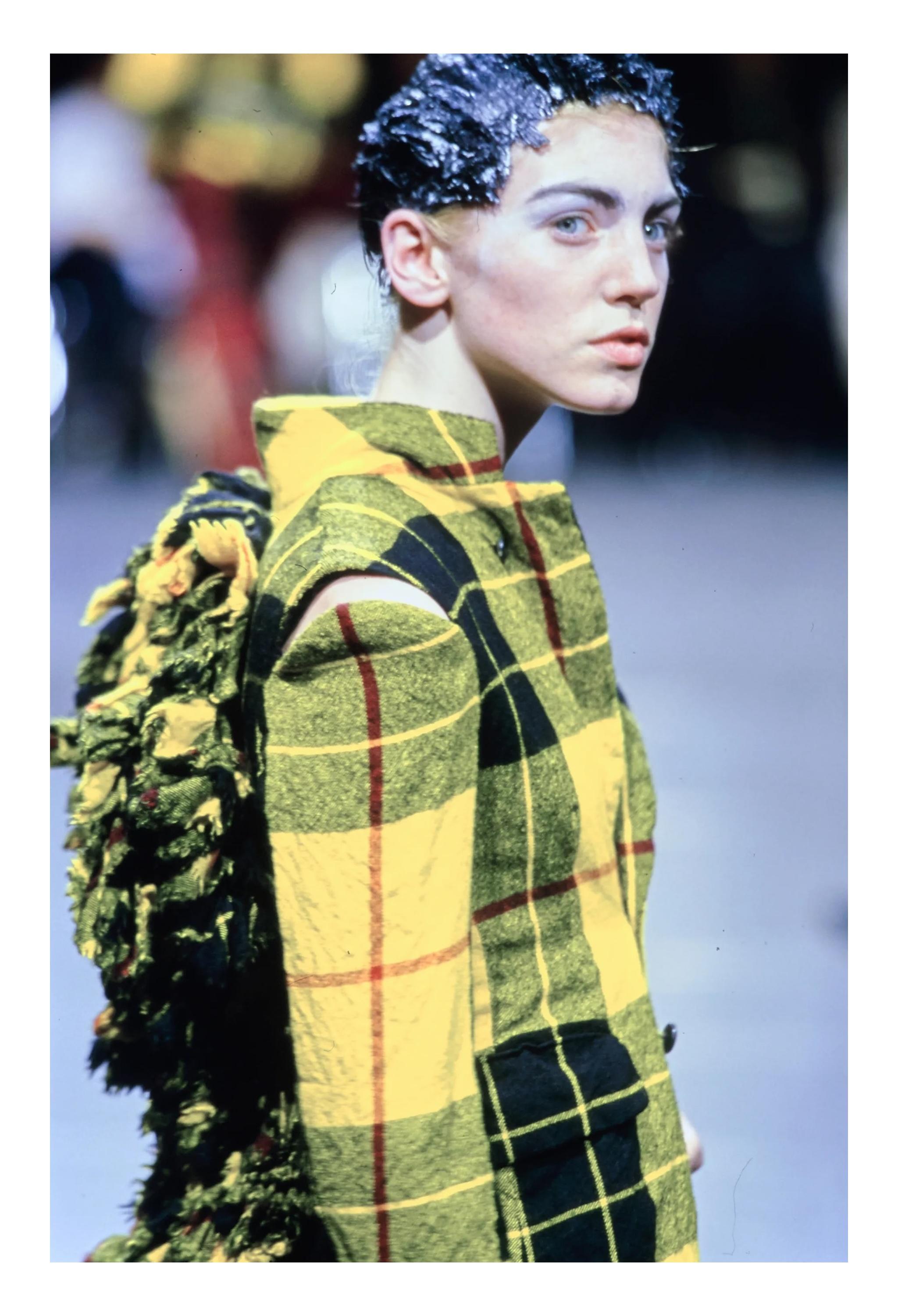 Resurrection Vintage è lieta di presentare un completo giacca e gonna tartan con volant di Comme Des Garçons della collezione FW 2000. La giacca presenta i caratteristici ritagli sotto le ascelle, la schiena arricciata, la chiusura a monopetto e due