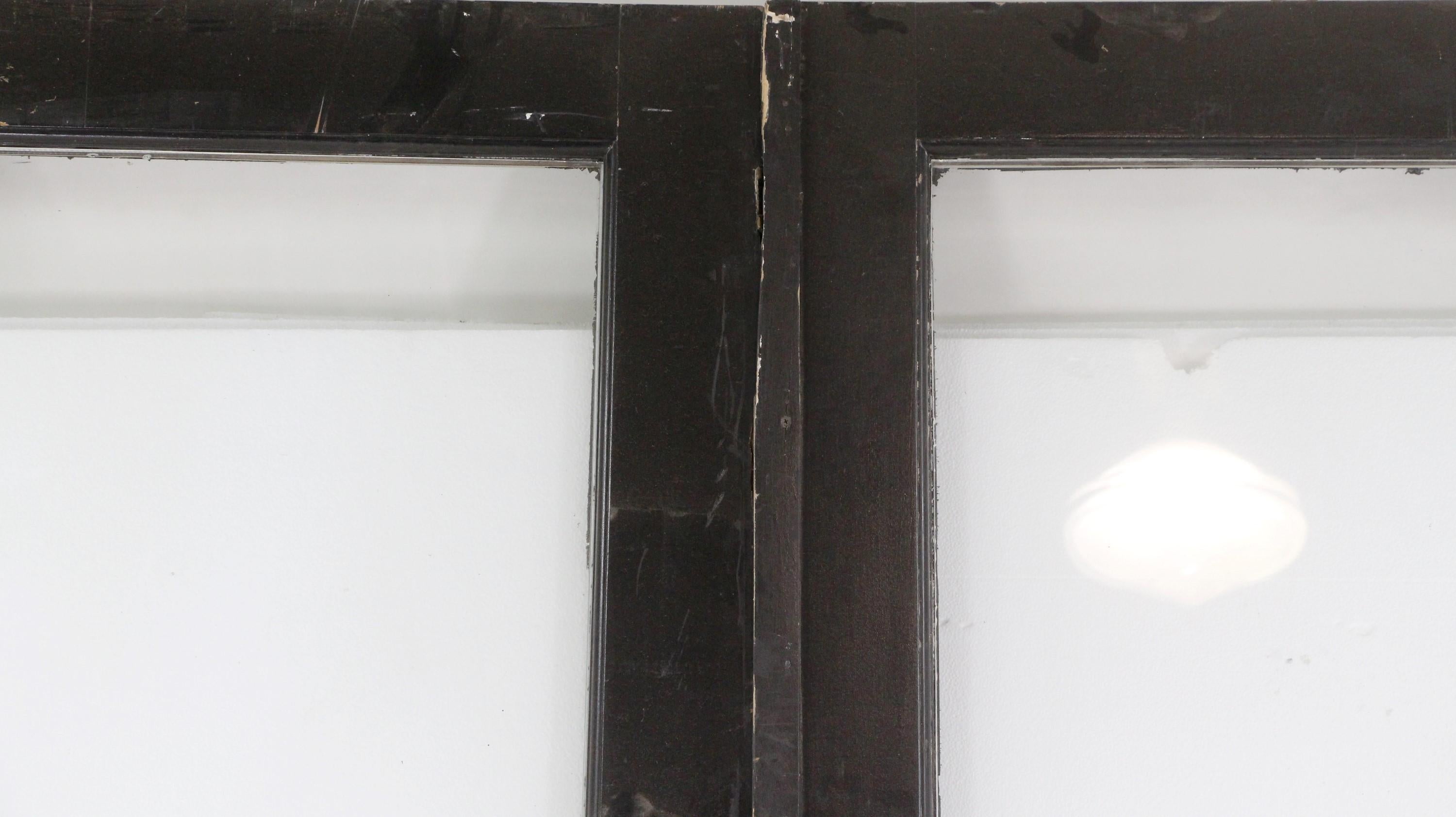 Antique black painted double doors with tall vertical glass lite and smaller bottom wood pane. The right front side of the door is stamped 