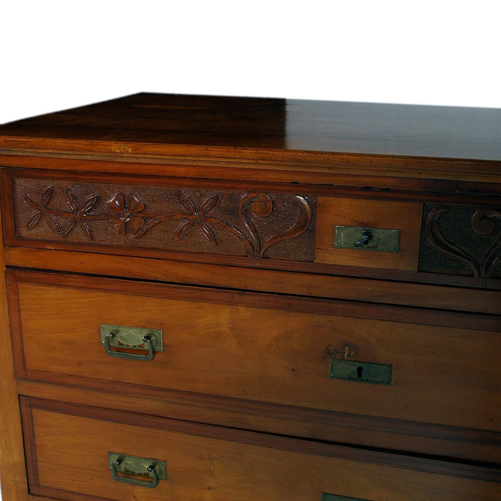 Elegant Art Nouveau chest of drawers, by Bassano's Ebanistery in solid walnut with four large drawers with dovetail sides; hand-carved front with floral motifs on the first drawer with key lock. Excellently made piece of furniture,