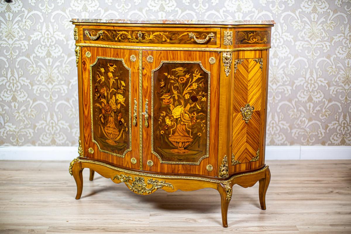 Inlaid Commode from the Late 20th Century in the Louis XV Type with Marble Top

We present you a high commode stylized as Louis XV.
This piece of furniture is two-leaf, with a drawer under the top, and topped with a marble board.
What draws