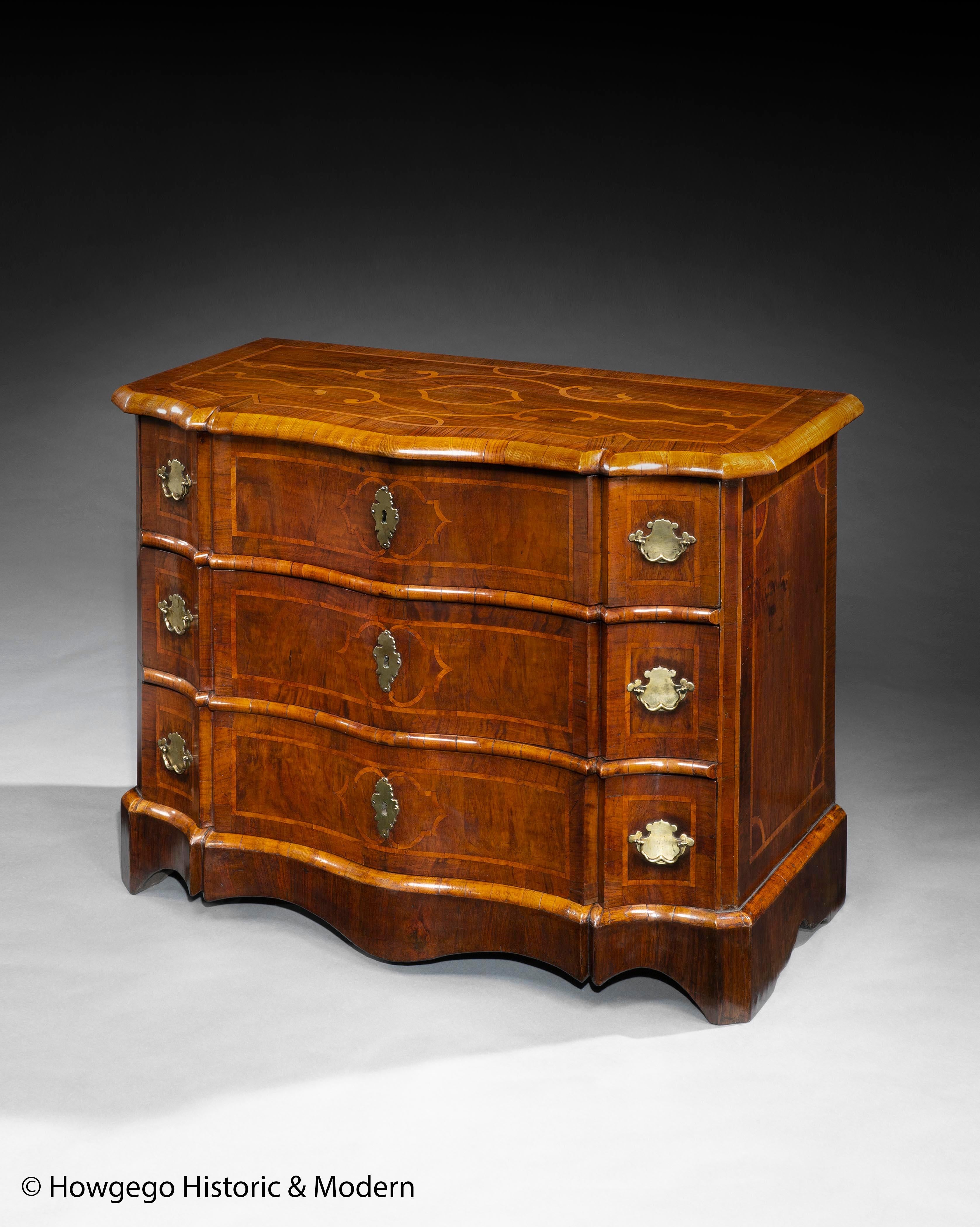 The serpentine front on this magnificent commode is sophisticated and gives it gravitas. The undulating form is a masterpiece of carpentry.
The carpenter has used different woods figuring to create a balanced mix of patterning; rosewood, walnut,