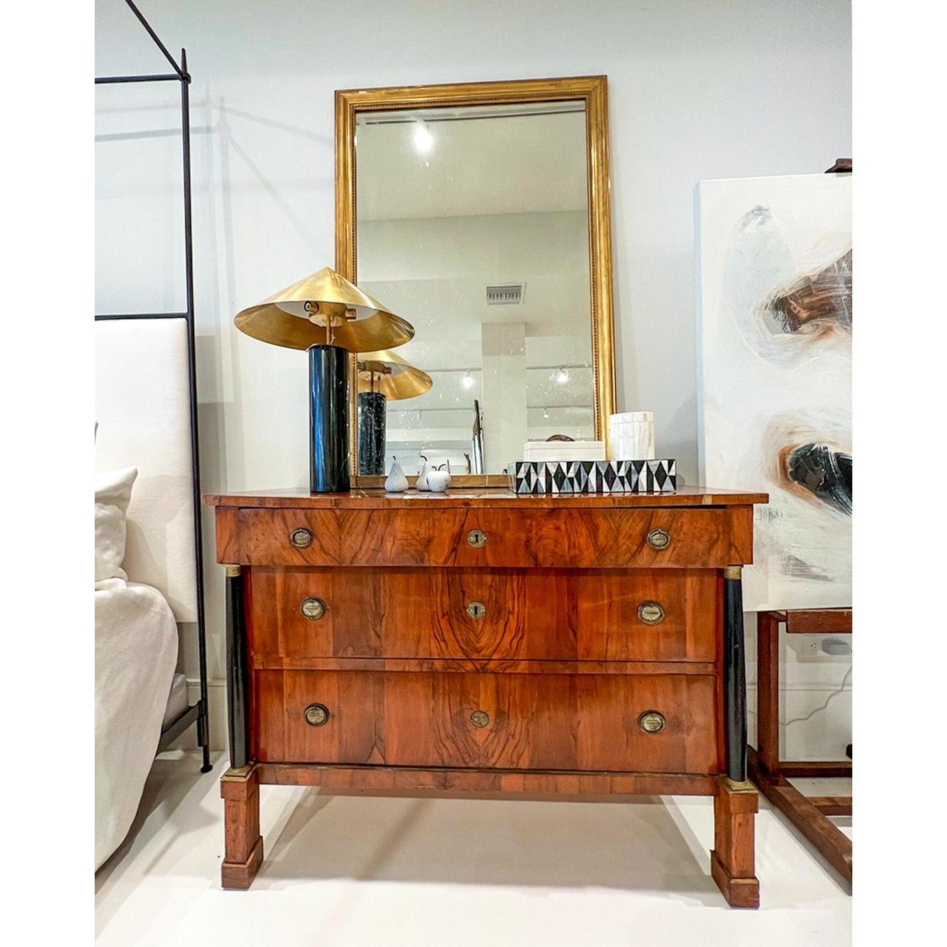 This is a beautiful Empire commode; a rare find. Warm walnut with book matching on the front drawers accented with bronze fittings.
It also has black columns on either side of the drawers topped with bronze capitals.
 
