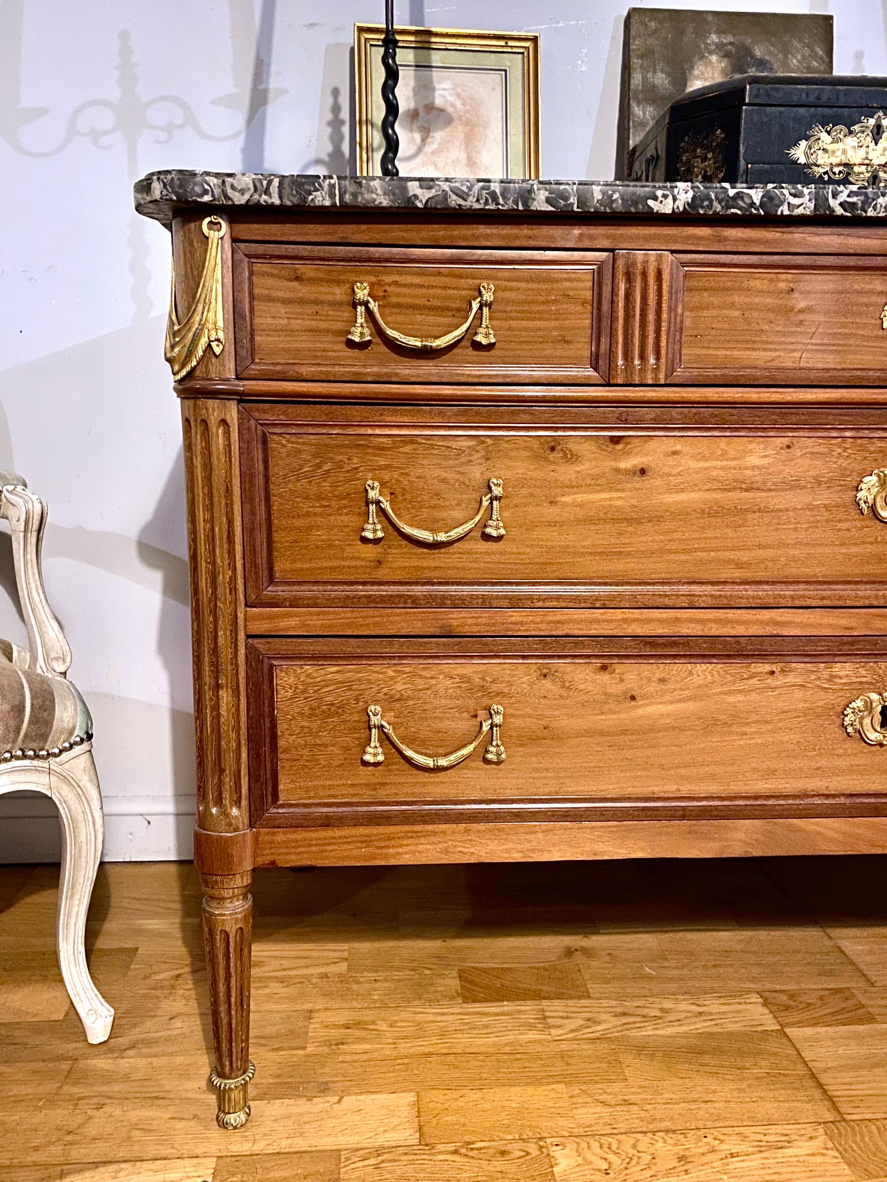 Superb Louis XVI style chest of drawers in mahogany and mahogany veneer covered with a very beautiful black and withe Saint Anne marble. The bronzes are in rare drapery and trimmings motifs. The amounts are fluted as well as the feet, the latter are