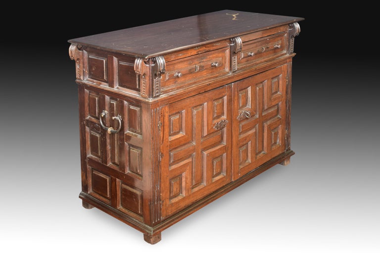 Locker Walnut wood, wrought iron. Spain, 17th century. 
Rectangular low furniture made of oak with elements in wrought iron that rises slightly on four legs, has a slightly protruding straight top board and fronts decorated with carvings, and has