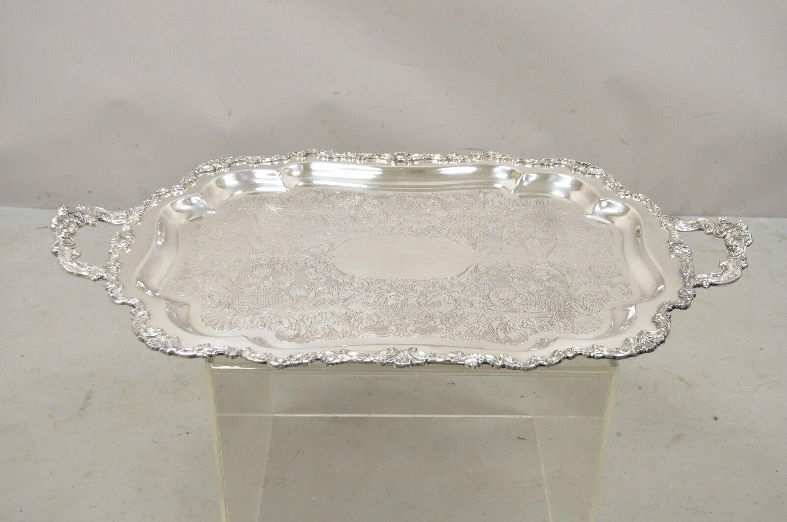 Comunidad Vintage Ascot 0316-10 Bandeja ornamentada con dos asas plateadas para servir. El artículo presenta un tamaño grande e impresionante, asas gemelas ornamentadas y una elegante forma festoneada. Mediados del siglo XX. Medidas: 2
