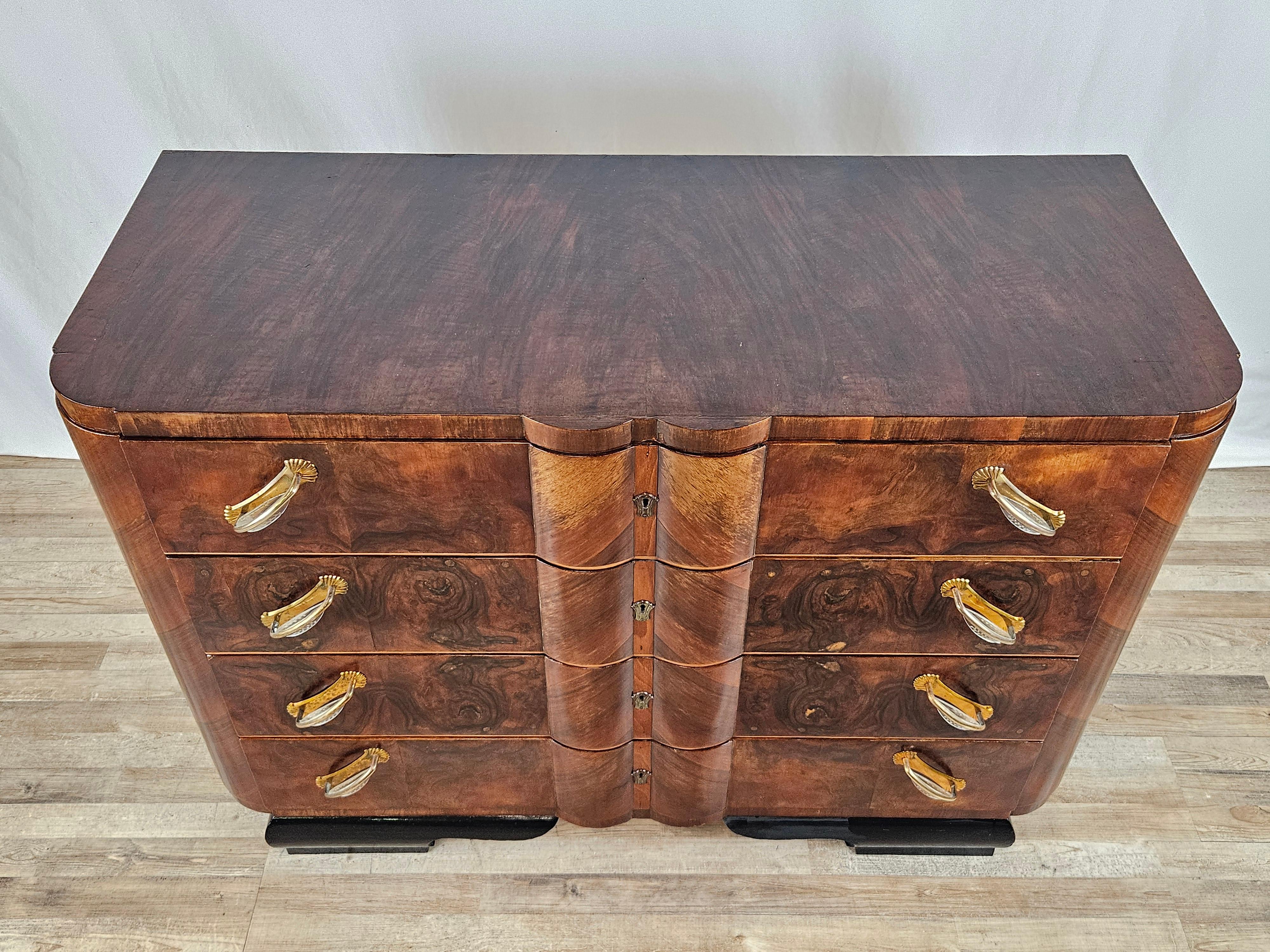 Elegant chest of drawers from the 1930-1940s in walnut burl with black lacquered feet and four wide, sturdy drawers decorated with brass and clear plastic handles.

The cabinet thanks to the refined design can be placed in any kind of room with