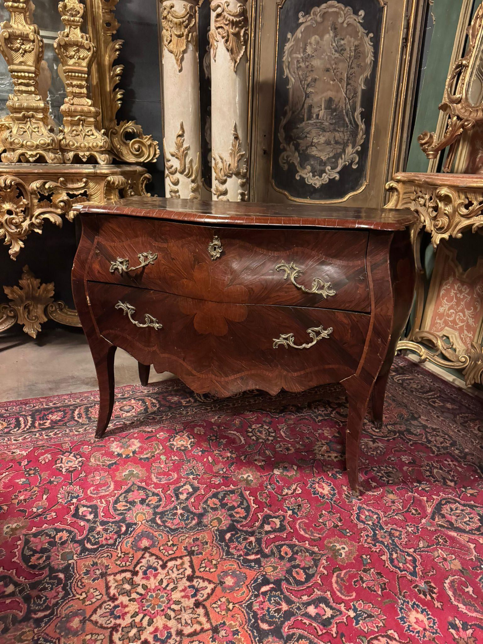 Antico Comò cassettone bombato in legno di noce, comò mosso, è lastronato in radica di noce e intarsiato con quadrifoglio sia superiore che davanti ai cassetti, presenta due cassetti completi di maniglie mosse in bronzo dorato. Grande valore