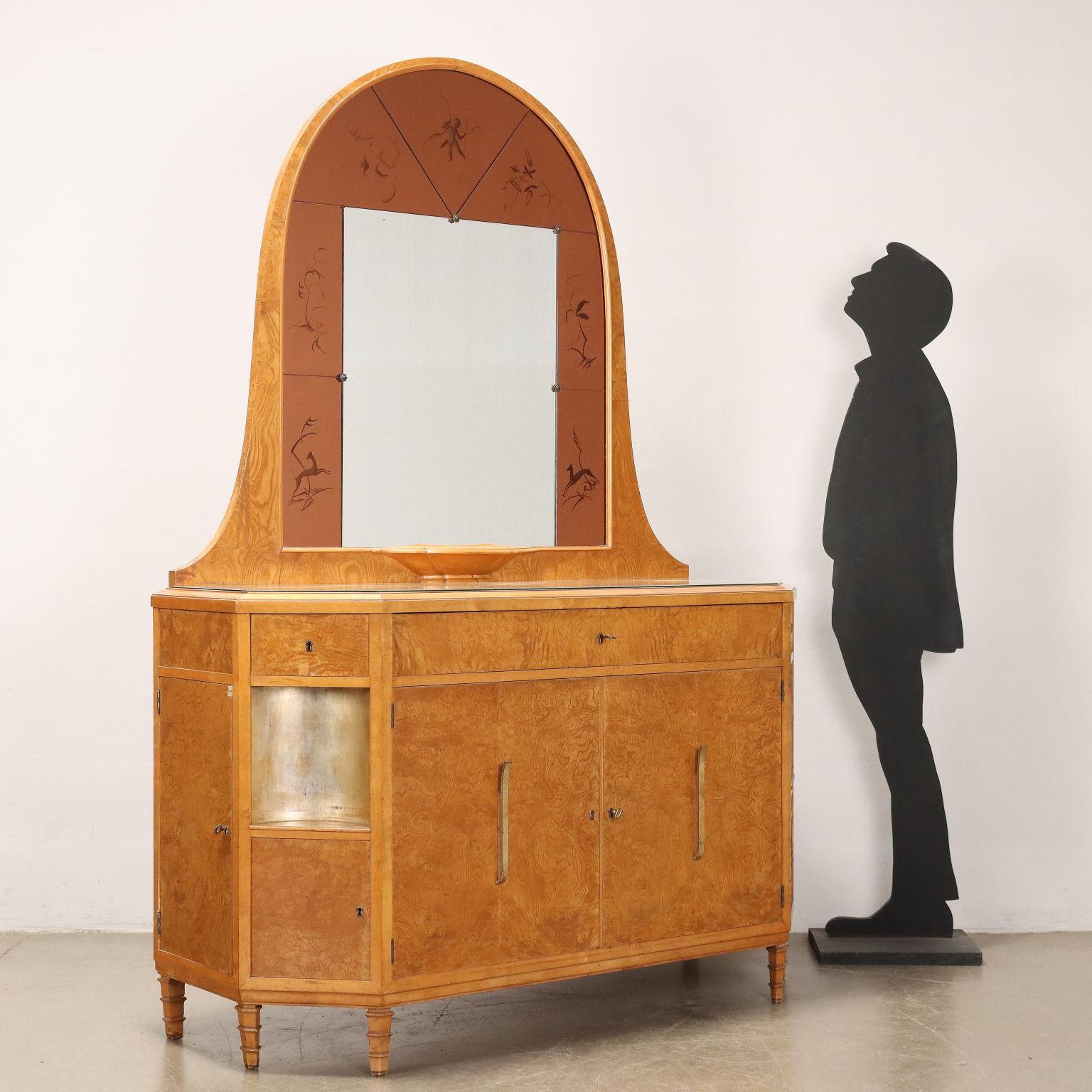 Elegante comò di manifattura italiana anni '40 '50 impiallacciato in radica. Presenta uno specchio incorniciato da vetri lavorati retro trattati, piano in vetro, ante a battente centrali che celano tre cassetti e piccole ante laterali; i piedi sono