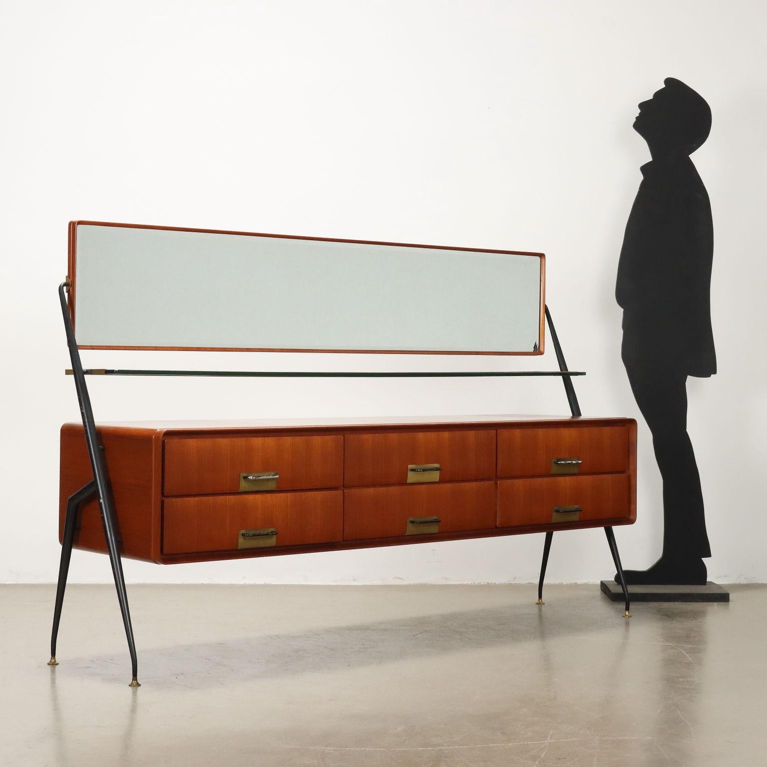 Comò con specchio basculante; ripiano in vetro, legno impiallacciato teak, gambe in metallo smaltato, maniglie in alluminio smaltato e ottone. Buone condizioni.