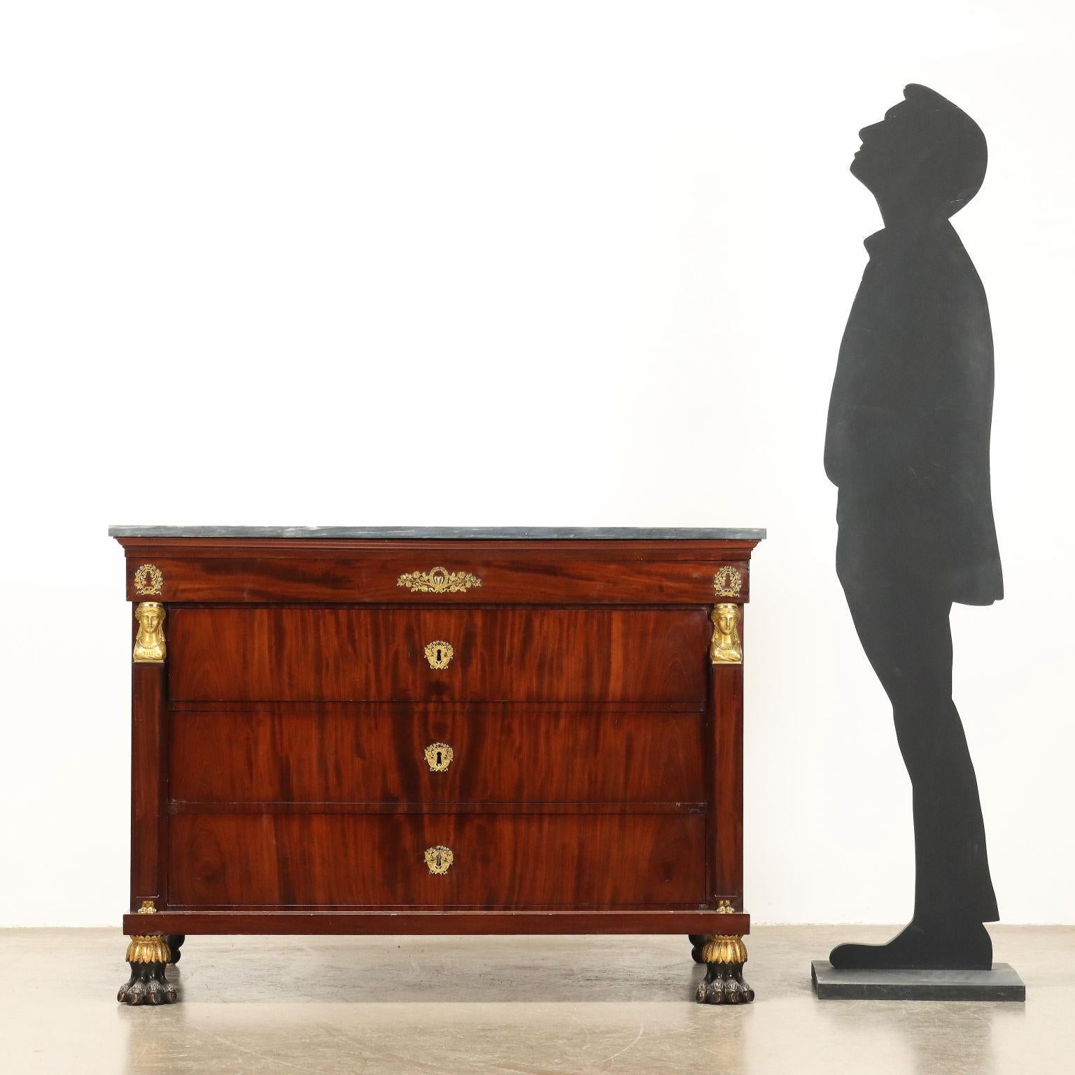 Commode Empire en acajou et noyer plaqué acajou, façade à quatre tiroirs dont le premier est en saillie, demi-colonnes à base pyramidale tronquée et chapiteau en bronze travaillé et doré. Embouchures et applications en bronze finement ciselé et