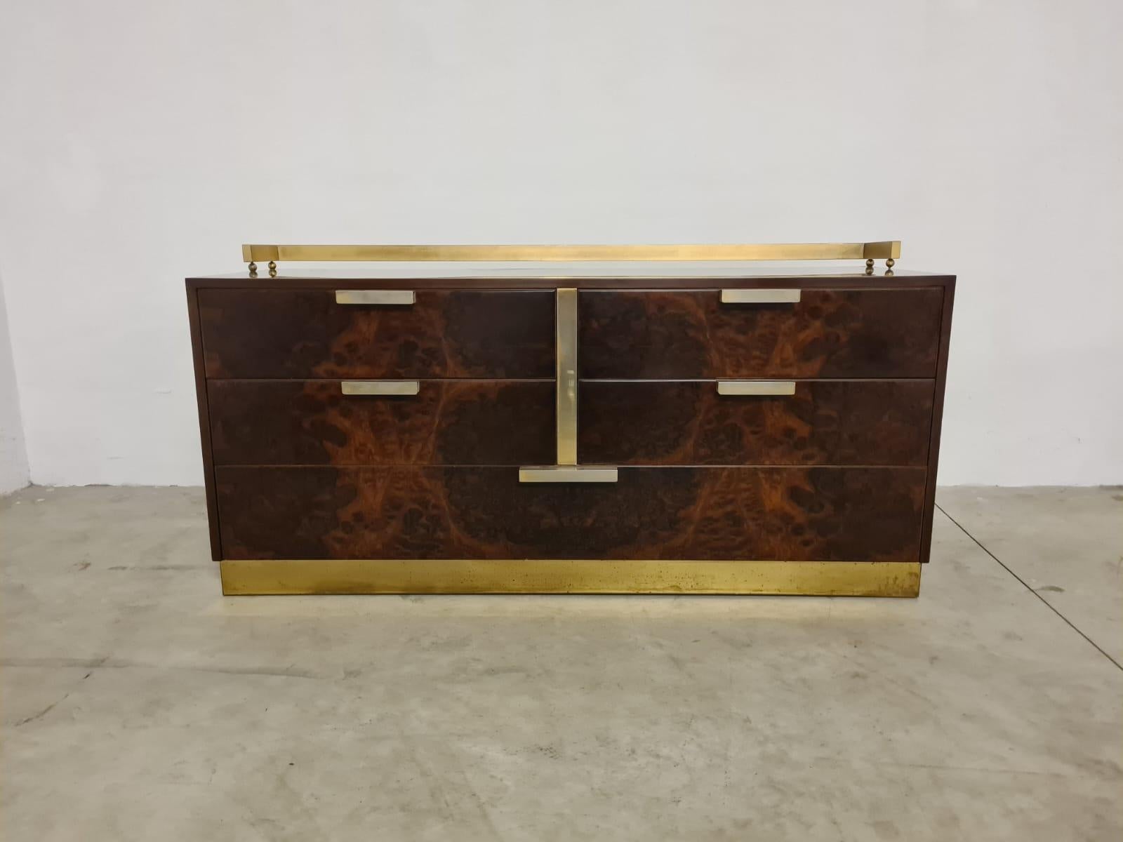 Commode Luciano Frigerio.

Une commode raffinée produite dans les années 1970 par Luciano Frigerio de Desio.

Fabriqué en bois de bruyère avec garniture en métal doré.

Equipé de 4 tiroirs supérieurs et d'un tiroir inférieur sur toute la