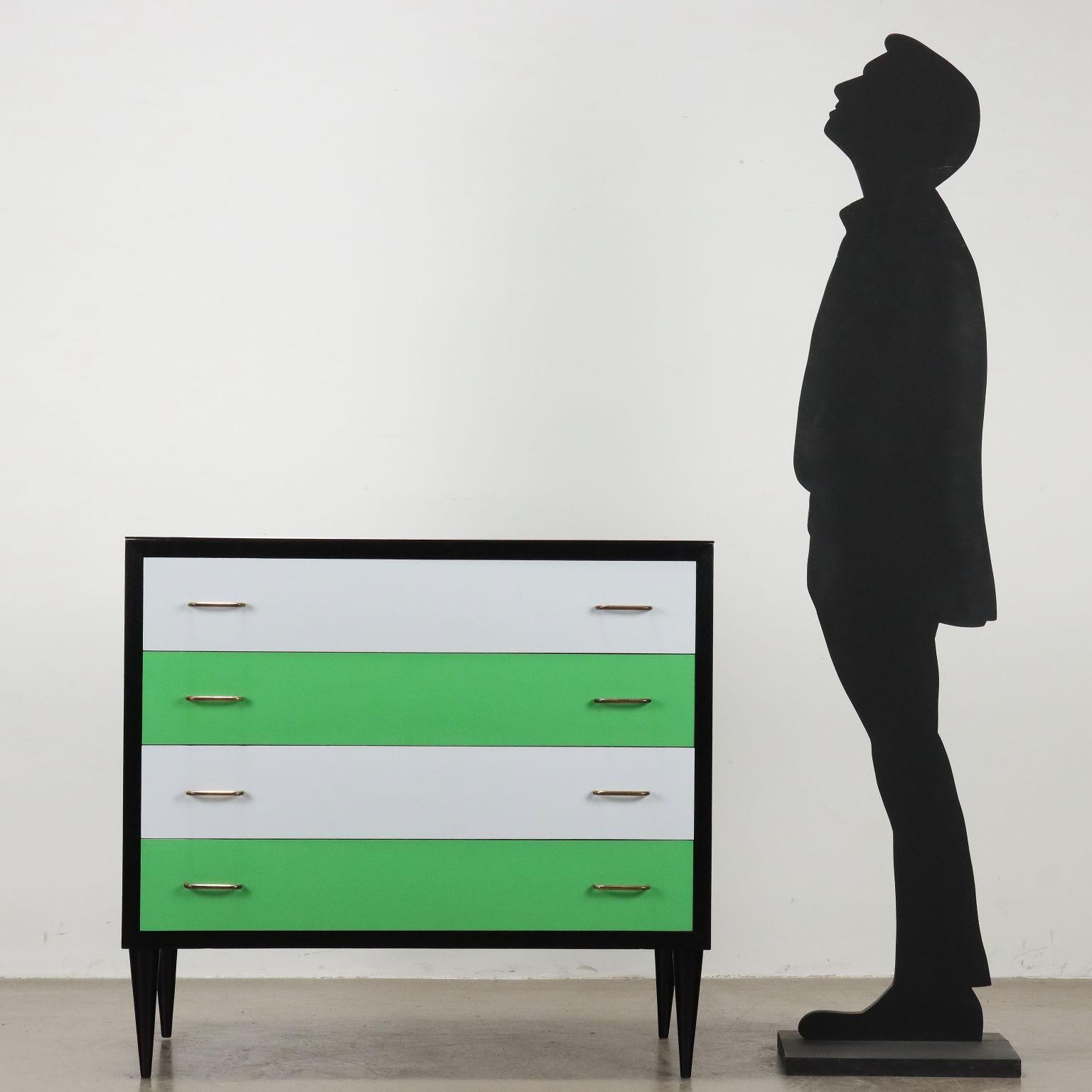Comò in legno impiallacciato di manifattura italiana, gambe in legno, cassetti in formica multicolore, rifinito ed ebanizzato nero. Piano in vetro a specchio nero fumé. 