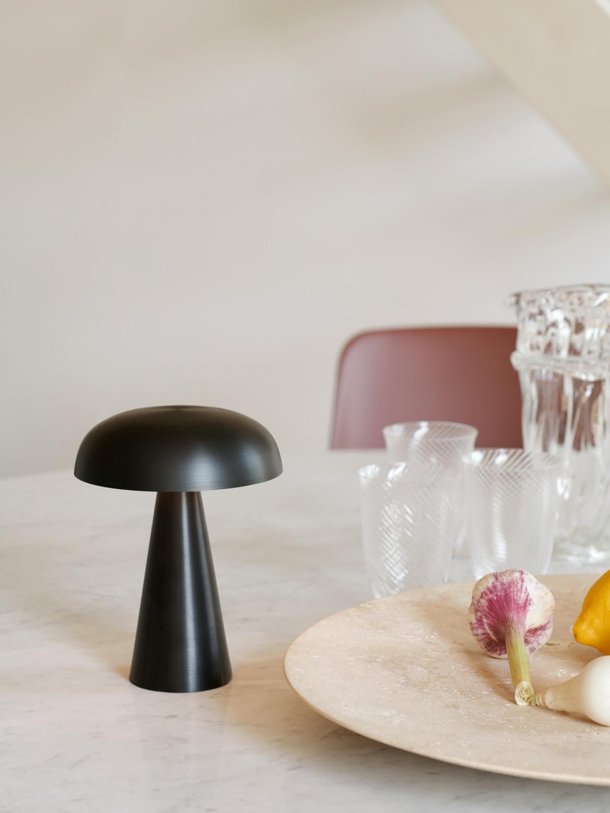 Match lighting to mood with Como SC53, a portable table lamp from Space Copenhagen. 
Crafted from anodized aluminium, Como’s sturdy base tapers up towards a softy curved, mushroom-shaped shade. 
This battery-powered lamp can operate for eleven hours