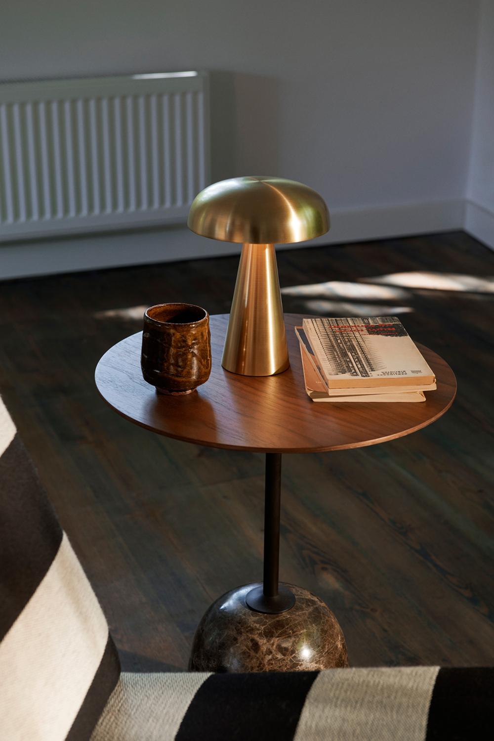 Como SC53, a portable Brass table lamp from Space Copenhagen. 
Crafted from anodized aluminium, Como’s sturdy base tapers up towards a softy curved, mushroom-shaped shade. 
This battery-powered lamp can operate for eleven hours at the highest