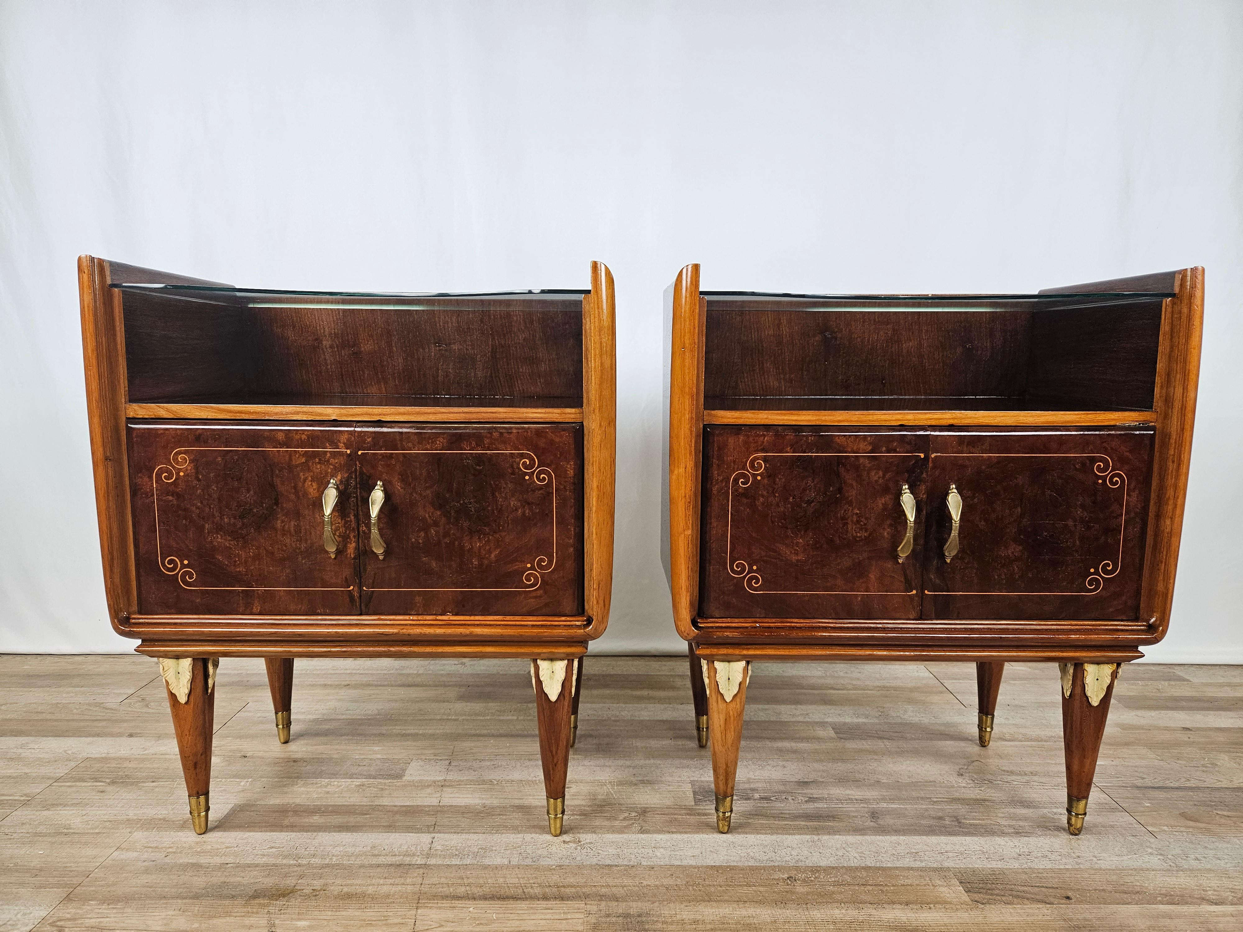 Peculiar pair of early 1950s bedside tables in walnut with maple details and inlays, enhanced by a curved clear glass top.

Elegant, for classy and designer environments.

Note the curved frame at the base of the laterals and the feet with wooden