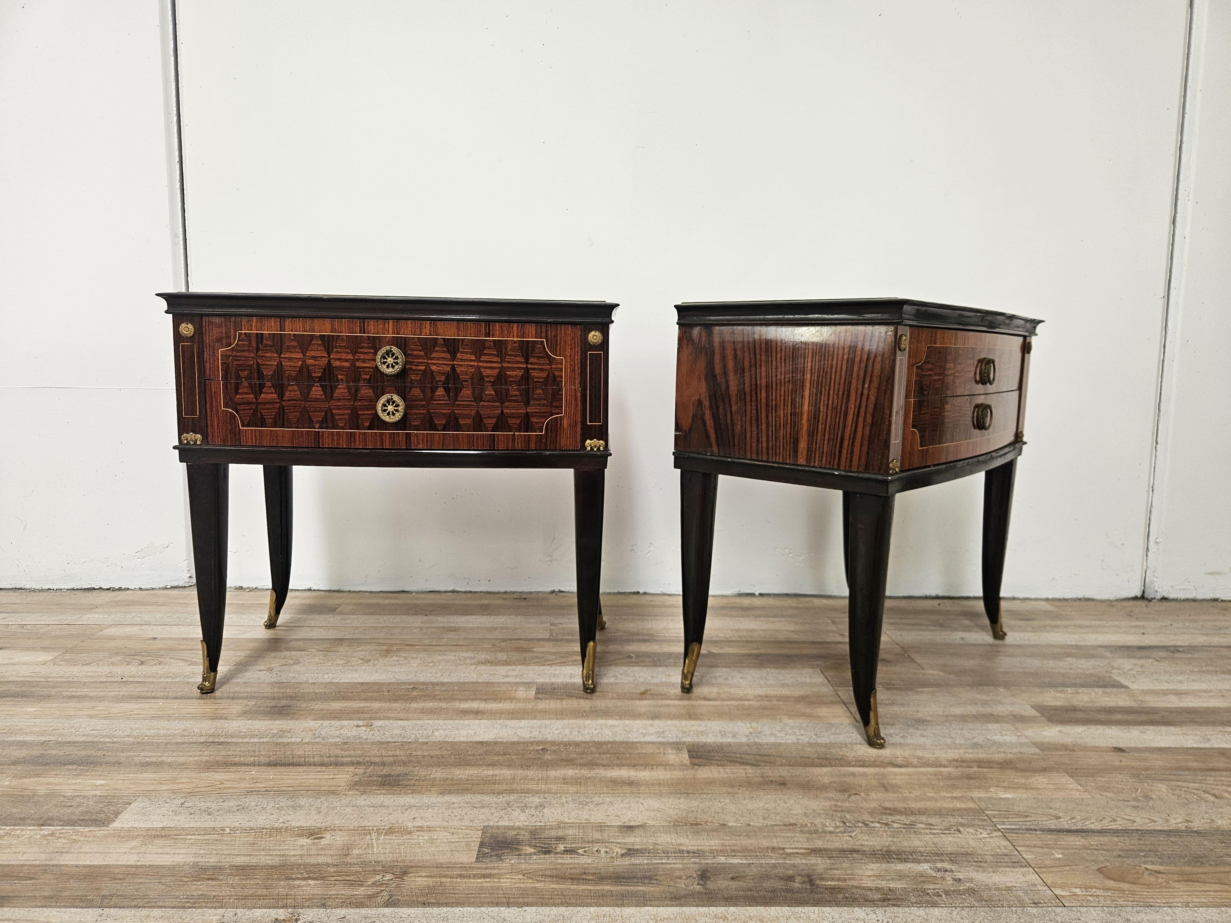 Pair of 1950s bedside tables upholstered in mahogany with ebony profiles and machined brass details.

On the main top they have a distinctive molded and decorated glass top, note the brass handles and foot props.

They have two wide and deep drawers