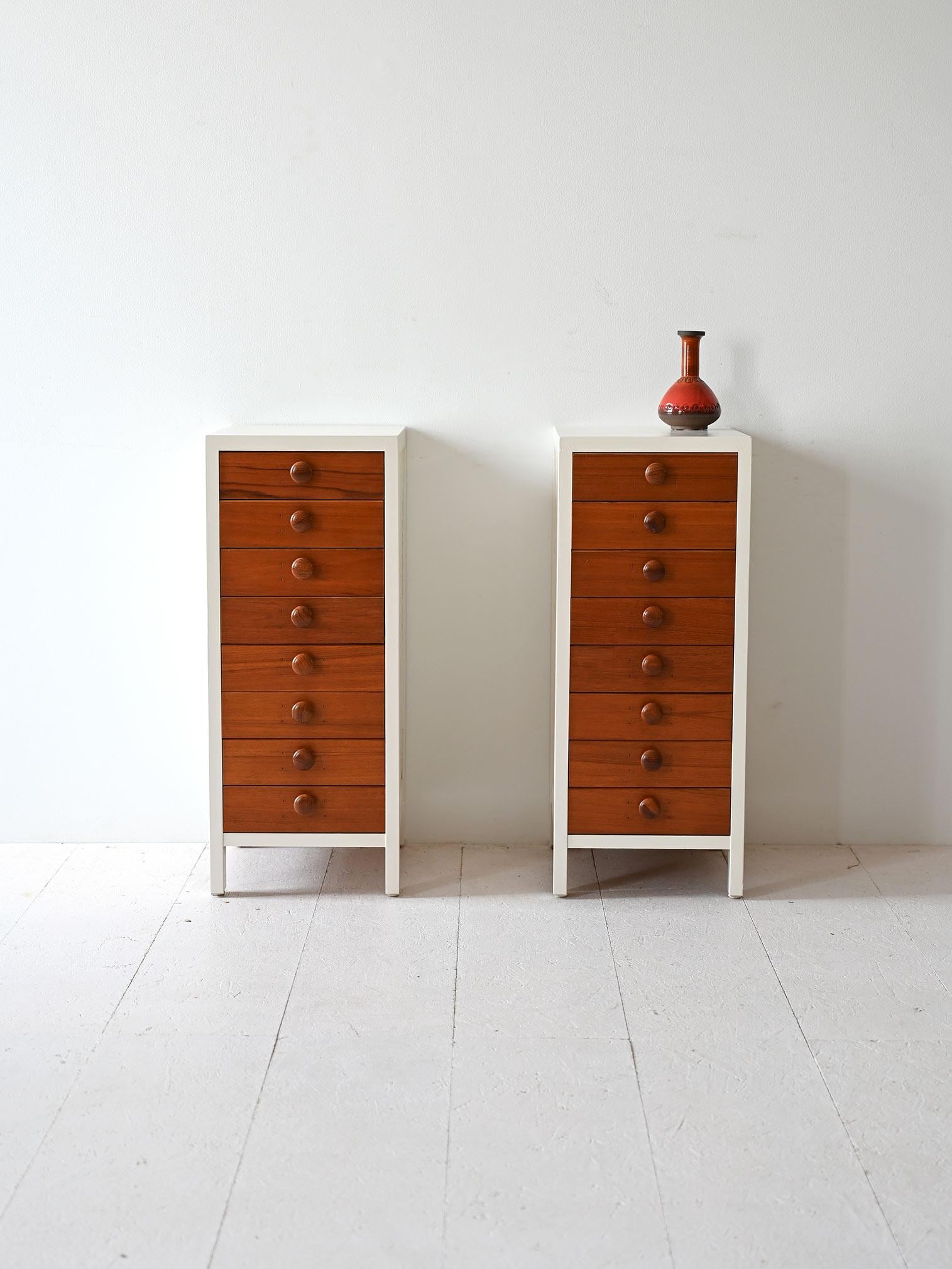 Pair of Scandinavian teak and white-painted wood nightstands, each featuring 8 drawers with round wooden handles.

Peculiar original 1960s chest of drawers that are distinguished by their elongated shape and the presence of numerous drawers with a