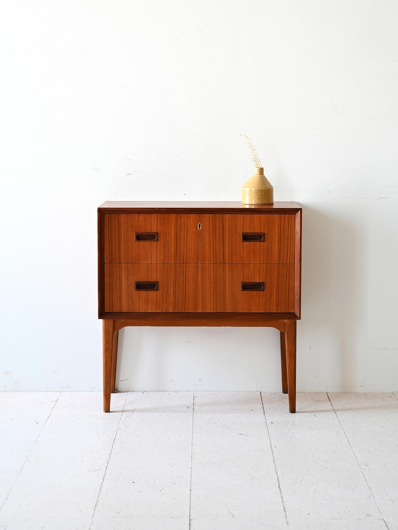 Mobiletto scandinavo in teak con due cassetti di cui uno dotato di serratura. Le gambe rastremate sono in legno di betulla. 

Le linee moderne e semplici lo rendono adatto a diversi stili. Perfetto come comodino ma anche come mobile per l'ingresso.