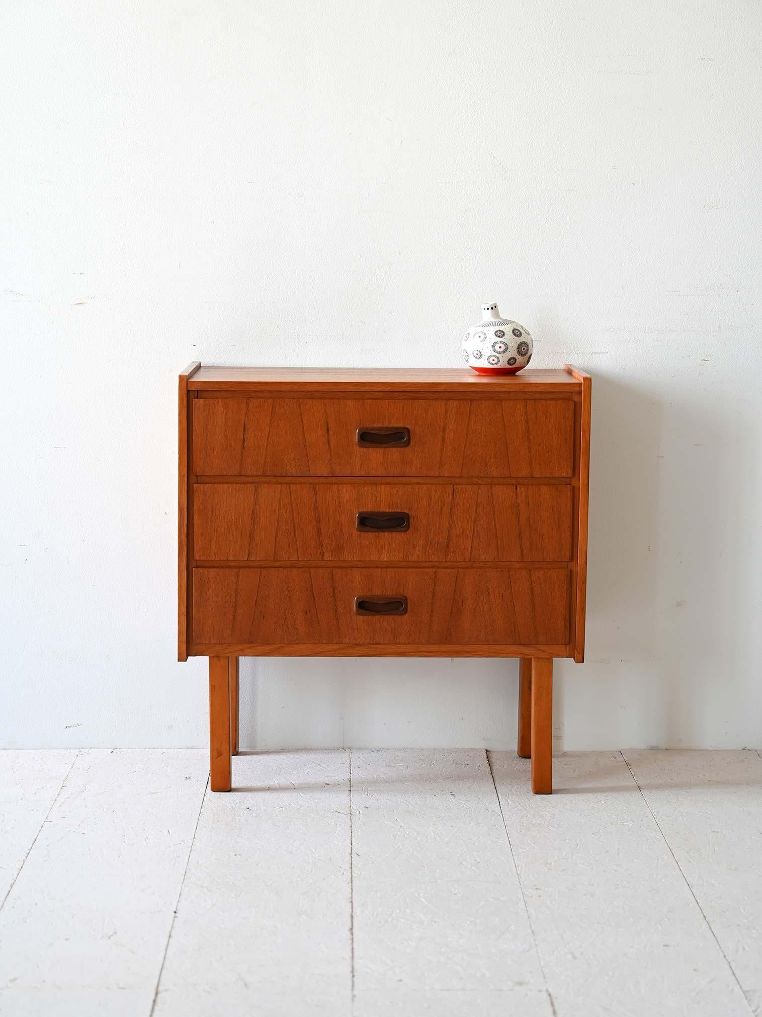 Kleine Kommode aus skandinavischem Teakholz mit geschnitzten Schubladengriffen und konischen Beinen. 

Das schlichte, moderne Design eignet sich für verschiedene Räume im Haus, um sie mit einem Hauch von Vintage zu dekorieren. 
Guter Zustand. Sie
