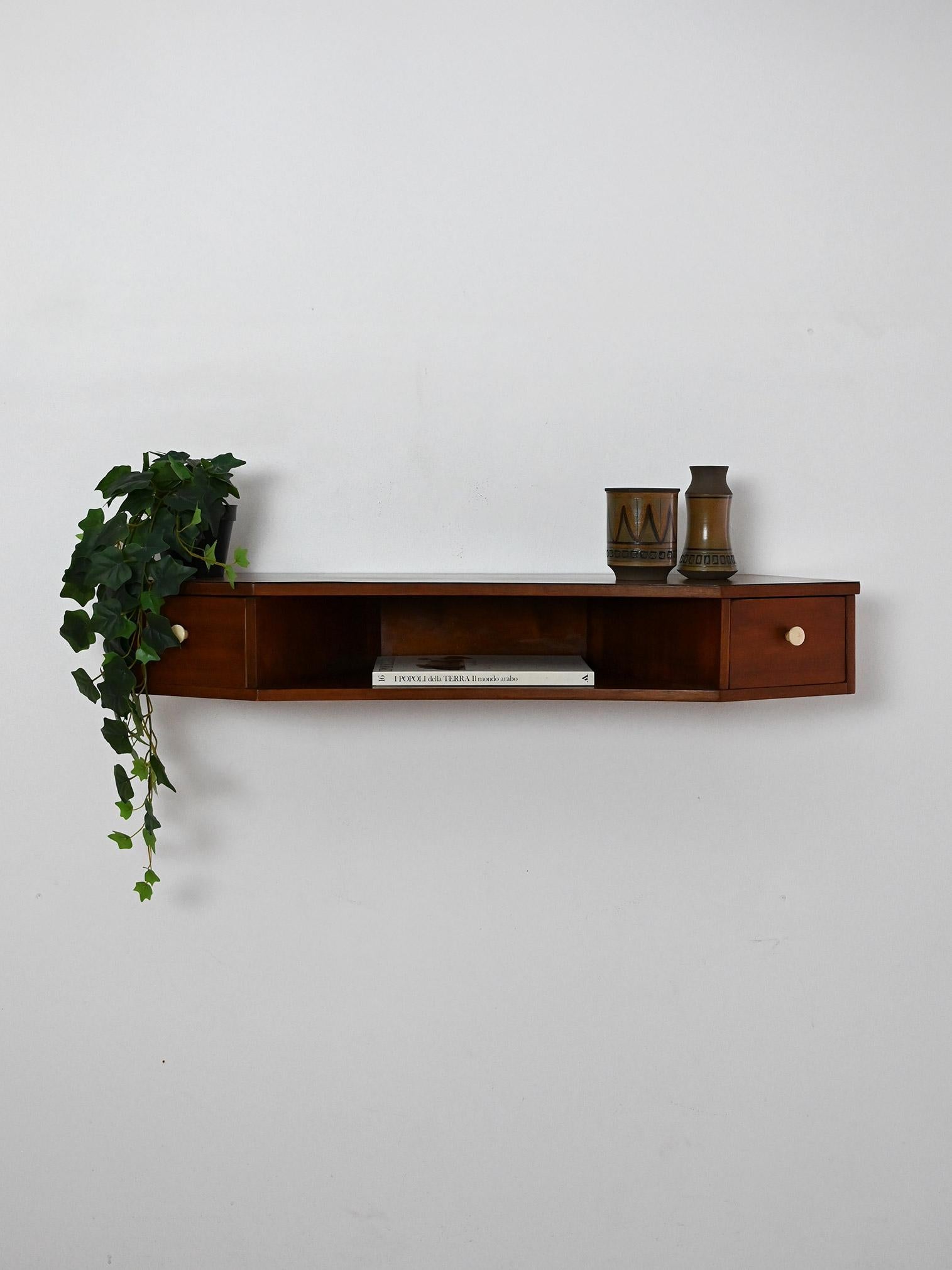 Table de chevet murale vintage des années 1950 en acajou avec deux tiroirs et boutons en bakélite. Des lignes élégantes et un profil profilé.

Table de chevet vintage en acajou scandinave avec deux tiroirs et boutons en bakélite ivoire. Le design