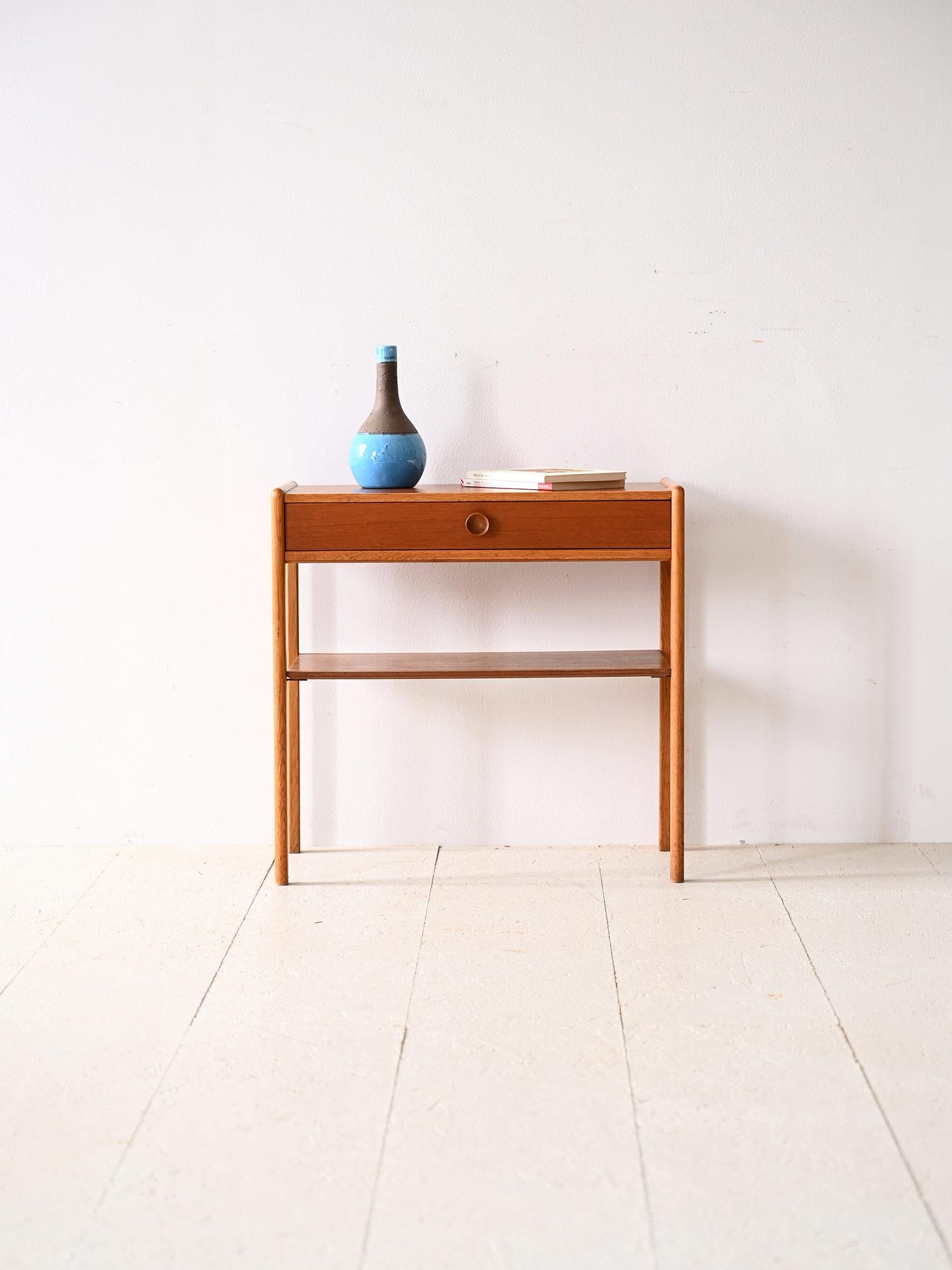 Scandinavian 1960s vintage nightstand.

A piece of modernism that traces the lines and taste of mid-century Scandinavian design.
The rectangular teak top features clear oak profiles that together with the legs create an interesting color effect and