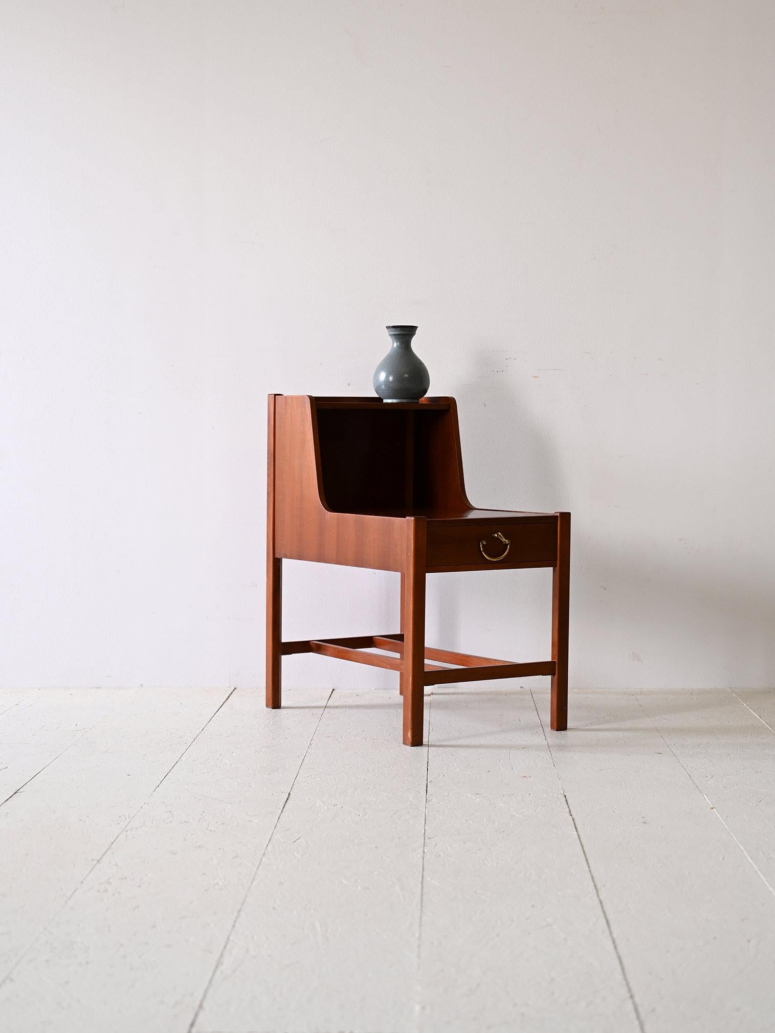 Swedish teak bedside table by David Rosén.

Its unusual shape, given by the double shelf, adds a distinctive touch, making it perfect for placing a lamp on the first shelf and keeping the second shelf free for other items. Square legs lend stability