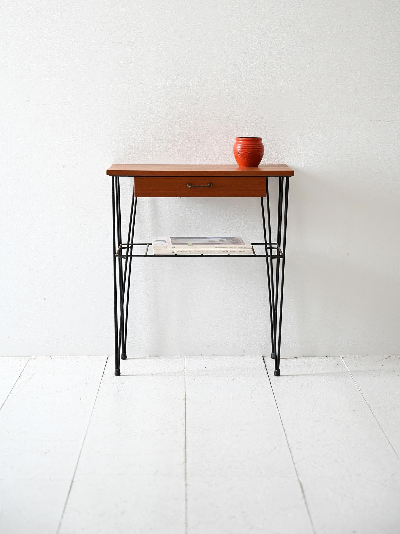 Comodino con piano in teak, struttura in ferro verniciato nero e mensola porta oggetti, anni 50/60.

Comodino scandinavo vintage risalente agli anni ’50/’60, con struttura in ferro verniciato nero e piano in teak. Dotato di un cassetto centrale con