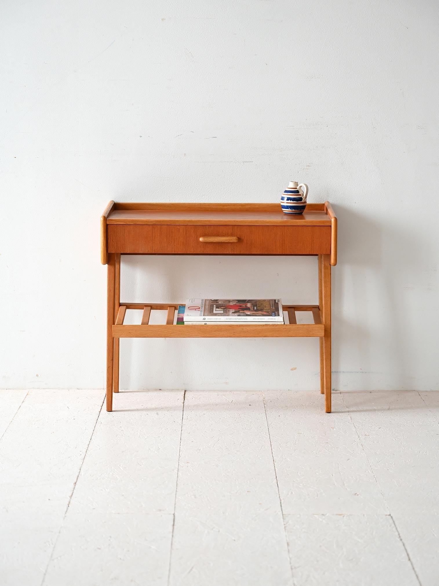 Scandinavian teak nightstand with drawer and slatted lower shelf. Lightweight structure with tapered legs and raised edge.

Scandinavian nightstand from the 1960s made of teak, with a central drawer and a slatted lower shelf for storing magazines or