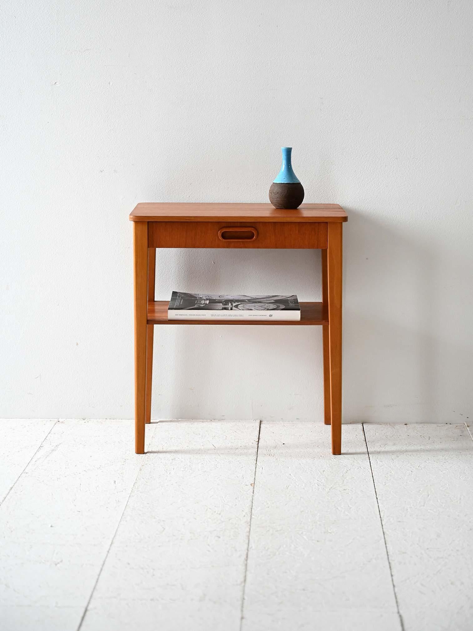 Comodino in teak anni 50/60 con cassetto e maniglia scolpita, dotato di mensola inferiore.

Comodino scandinavo vintage in teak risalente agli anni ’50/’60. Dotato di un cassetto con maniglia scolpita direttamente nel legno e una mensola inferiore