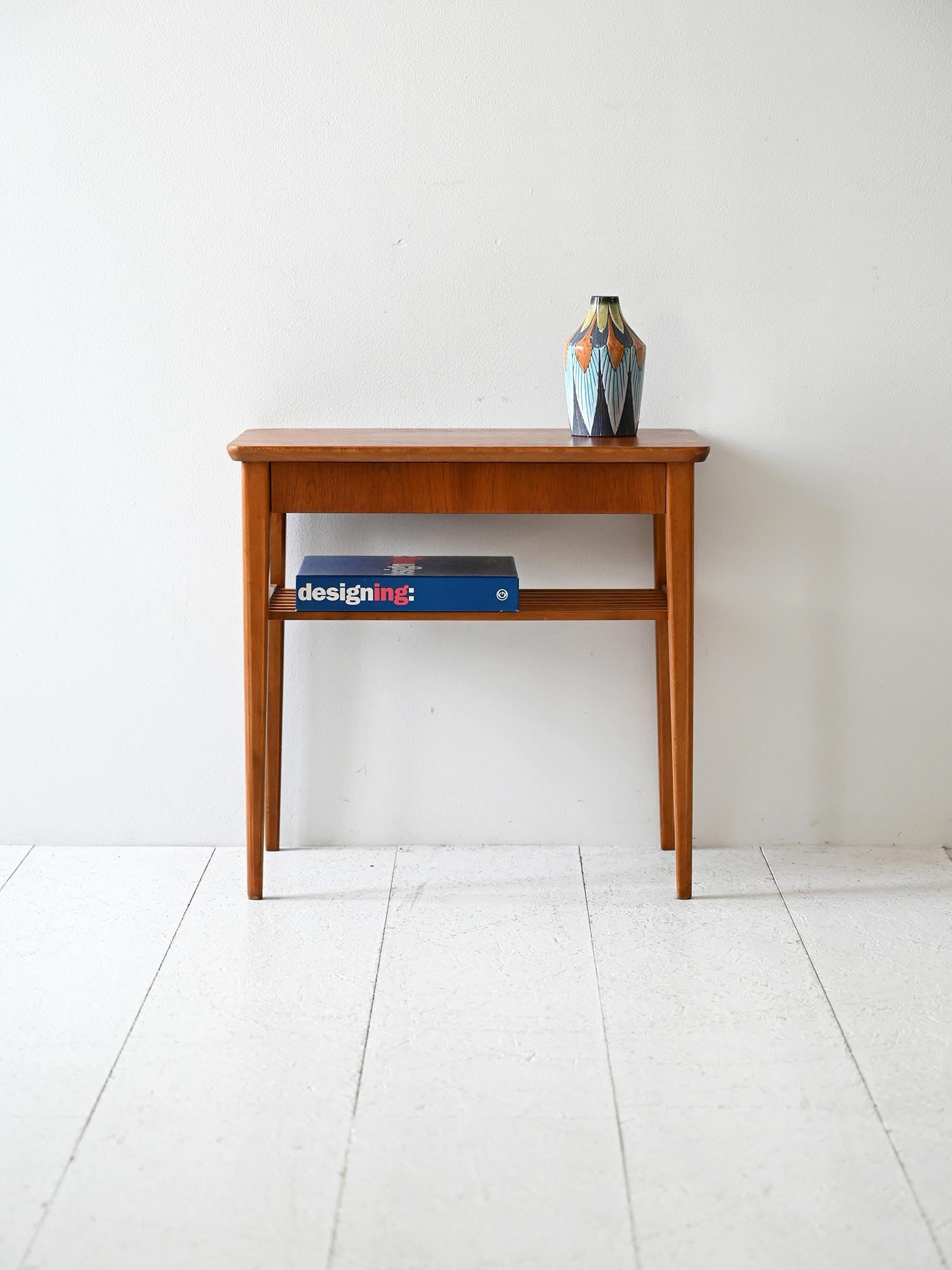 Comodino scandinavo in teak con mensola a listelli e cassetto a scomparsa, anni 50/60.

Comodino scandinavo vintage realizzato in teak, risalente agli anni ’50/’60. La struttura snella ospita una mensola inferiore a listelli orizzontali e un