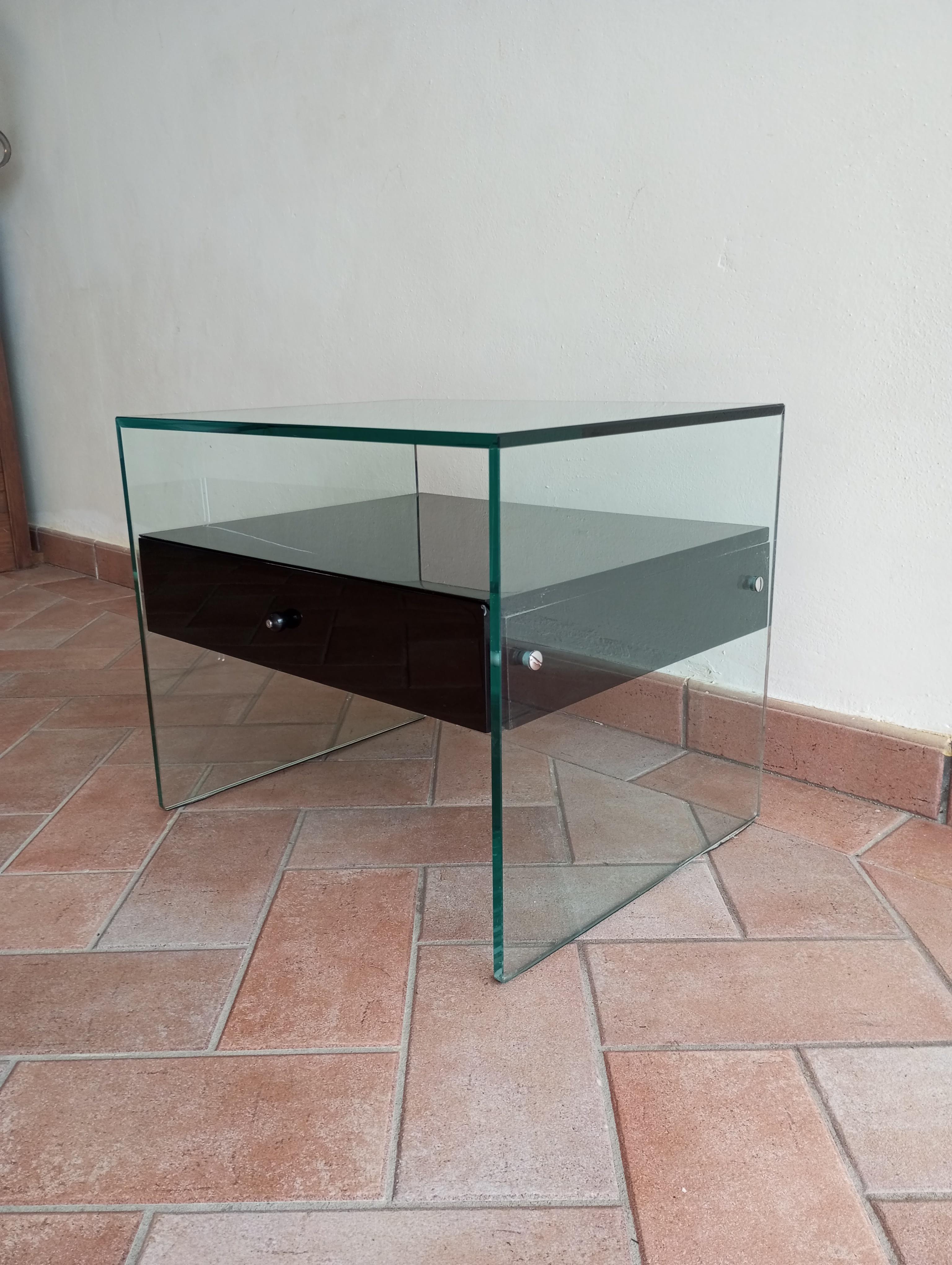 Secret' Nachttisch in minimalistischem Design, mit einer Brückenstruktur aus Glas. 
Die Glasplatten haben eine Brückenstruktur, die zentrale Schublade aus schwarz lackiertem Holz ist auf halber Höhe angebracht und bietet so eine zusätzliche