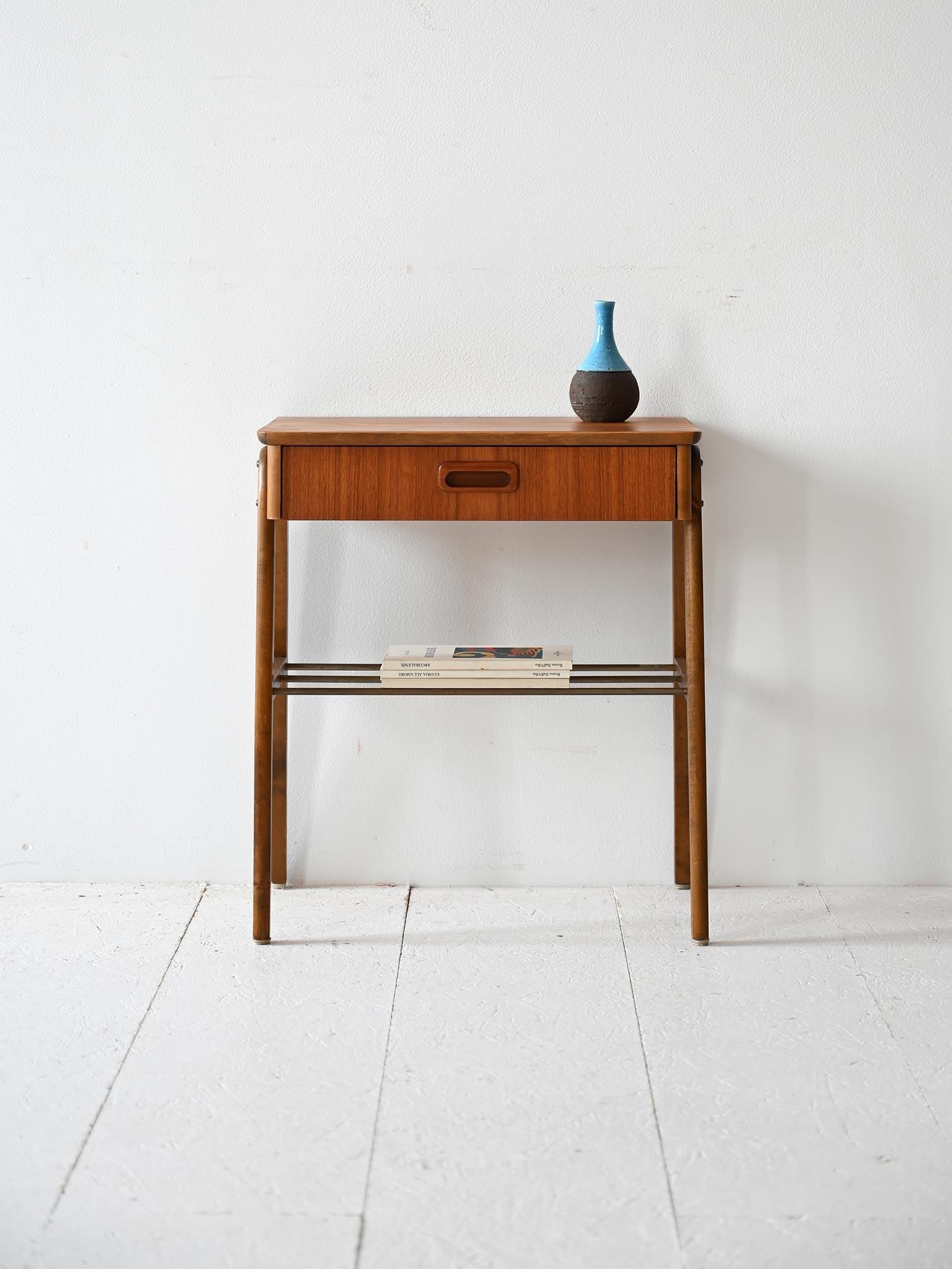 Table de chevet scandinave vintage avec un tiroir à poignée en bois sculpté et une étagère à magazines en lattes de bois.

Les lignes simples et modernes s'adaptent à différents styles et environnements. Elle peut également servir de table d'entrée