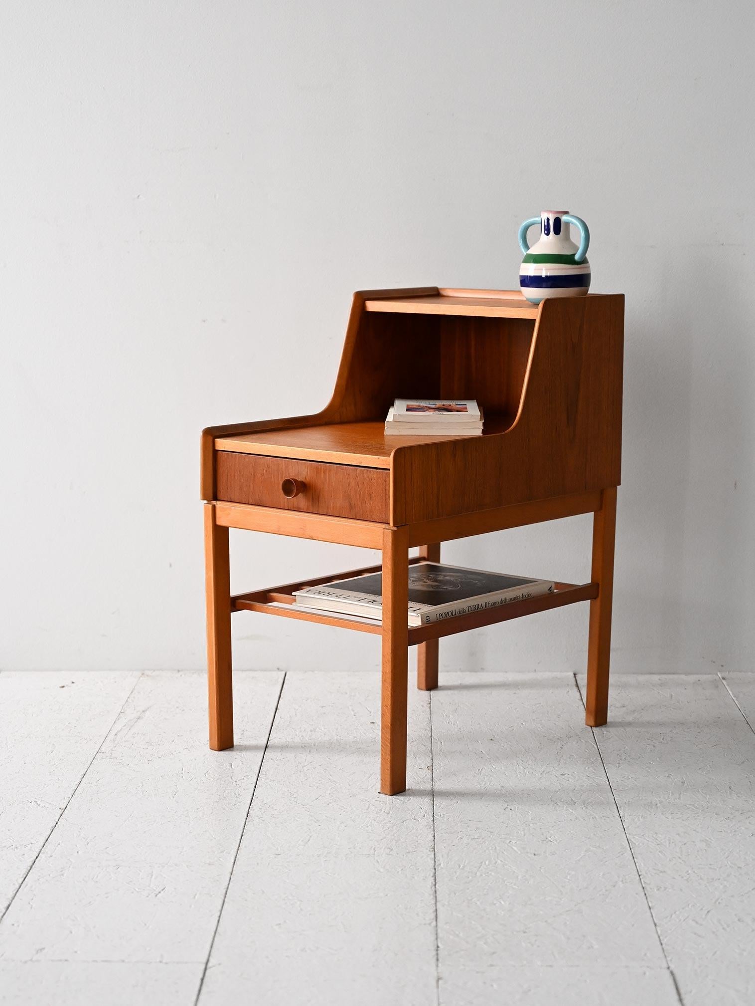 Table de chevet vintage en teck avec tiroir central, double étagère et poignée ronde sculptée en relief.

Table de chevet scandinave en teck des années 1960, à la structure compacte et bien conçue. La partie supérieure comprend une étagère ouverte,