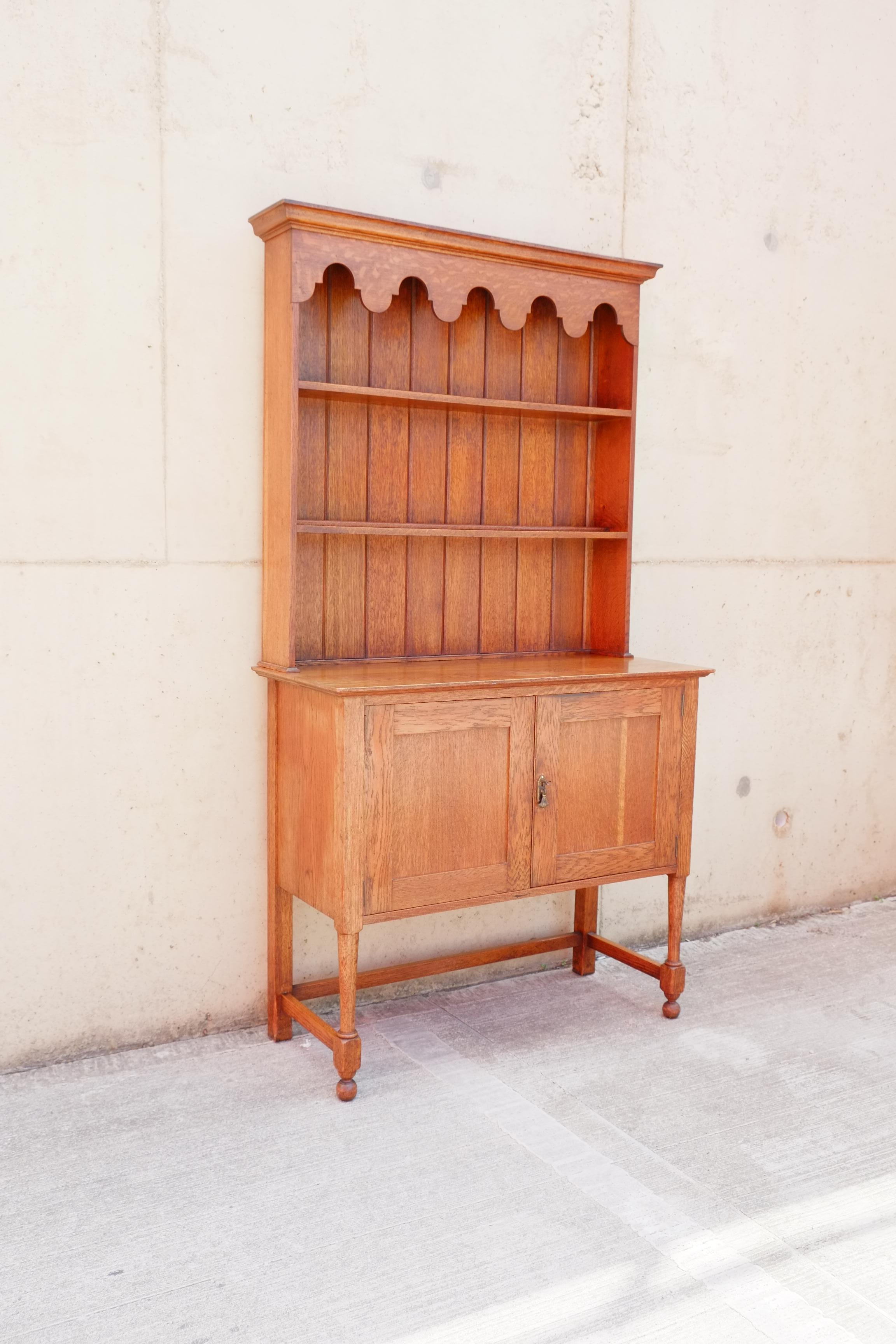 Voici une magnifique commode galloise compacte en chêne massif datant du début du 20e siècle. La commode galloise est dotée d'un petit placard en dessous et d'un porte-assiettes fin et élégant au-dessus, avec un détail de corniche des plus élégants.